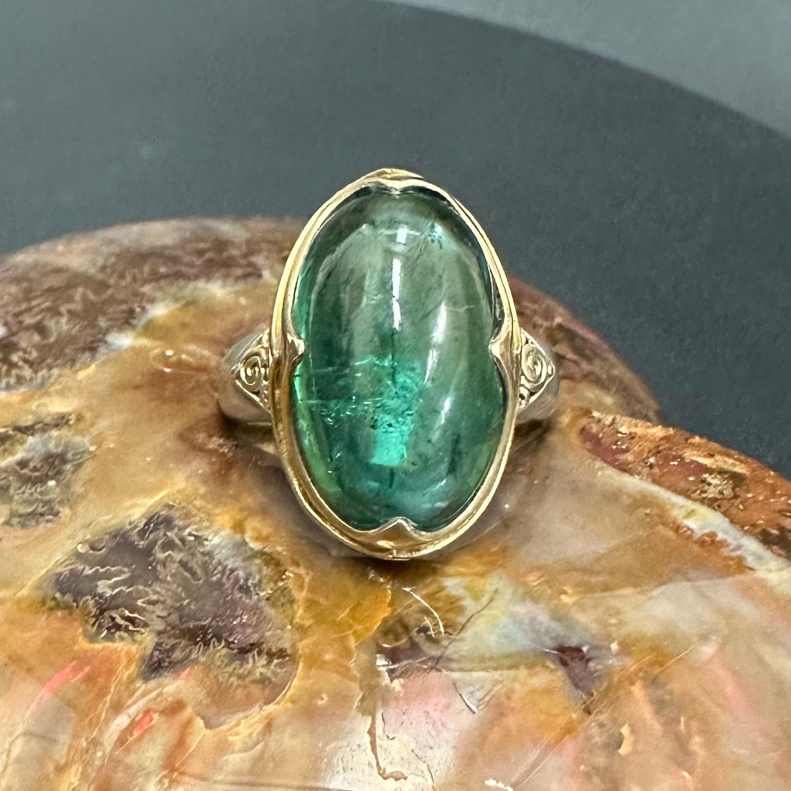 Un cabochon de tourmaline verte ovale de 11 x 19 mm de long est serti dans une monture longitudinale en or 18 carats d'inspiration médiévale 