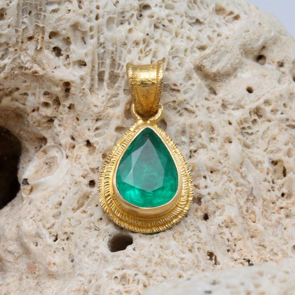 A brilliant high quality 7 x 9 mm pear shaped faceted Zambian emerald is held in in a signature handmade double line texture bezel in this simple yet classic look.  The 18K woven chain shown is not included but can the ordered additionally.  It