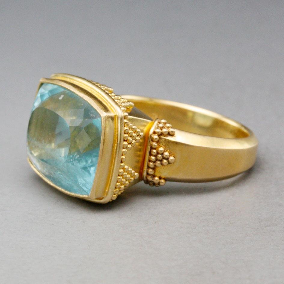 Ein wundervoller blauer 12 x 16 mm großer, kissenförmiger, facettierter Aquamarin ist horizontal in einer charakteristischen V-Fassung mit gestapelter geometrischer Granulation darunter gefasst und passt auch auf den flachen, konisch zulaufenden