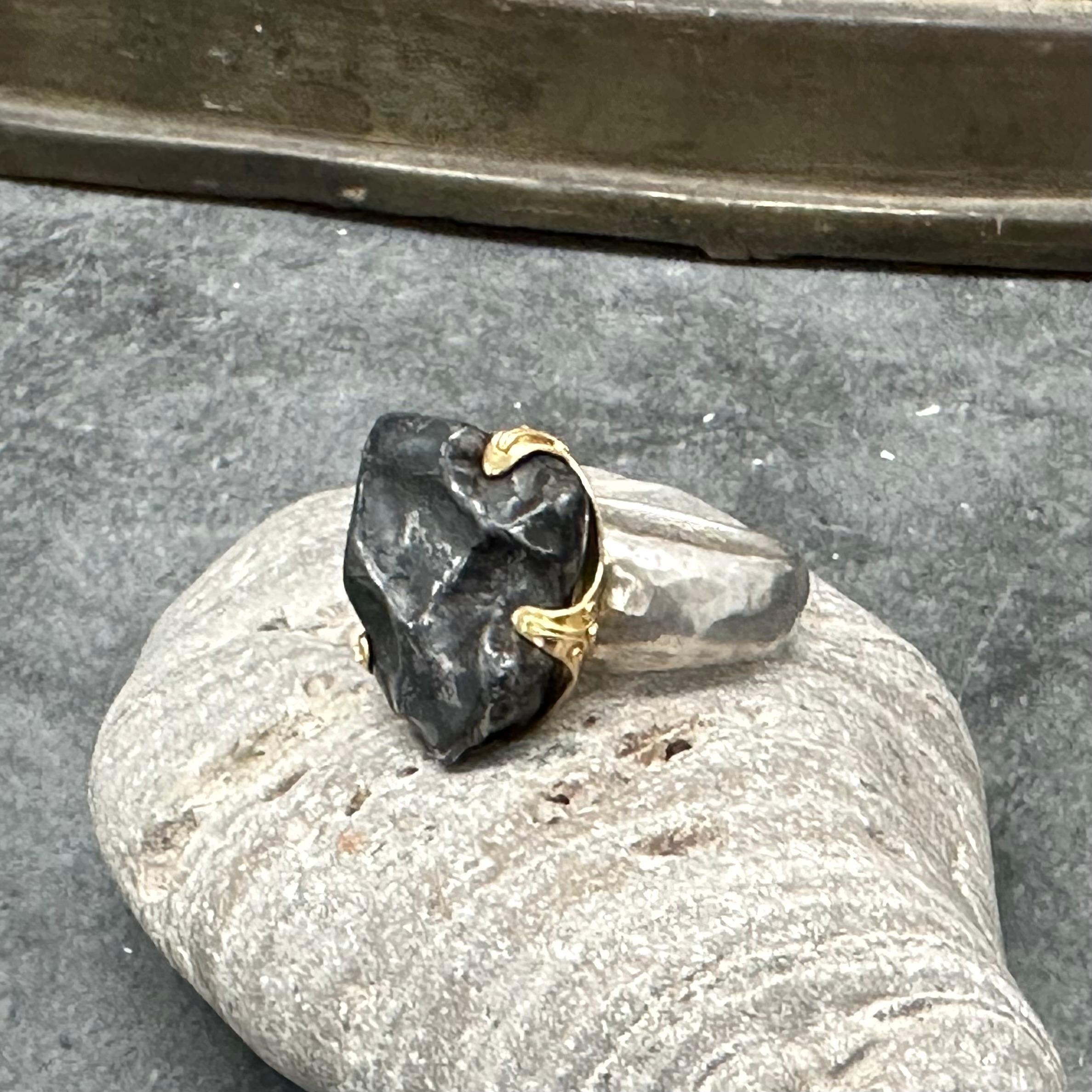 An individual irregular fragment (20 x 22 mm, 14.5 grams) of Sinkote-Alin meteorite with a fusion crust from its flaming entry through the atmosphere is set within a triangular 18K handmade prong setting with spiral accent wires above a heavy