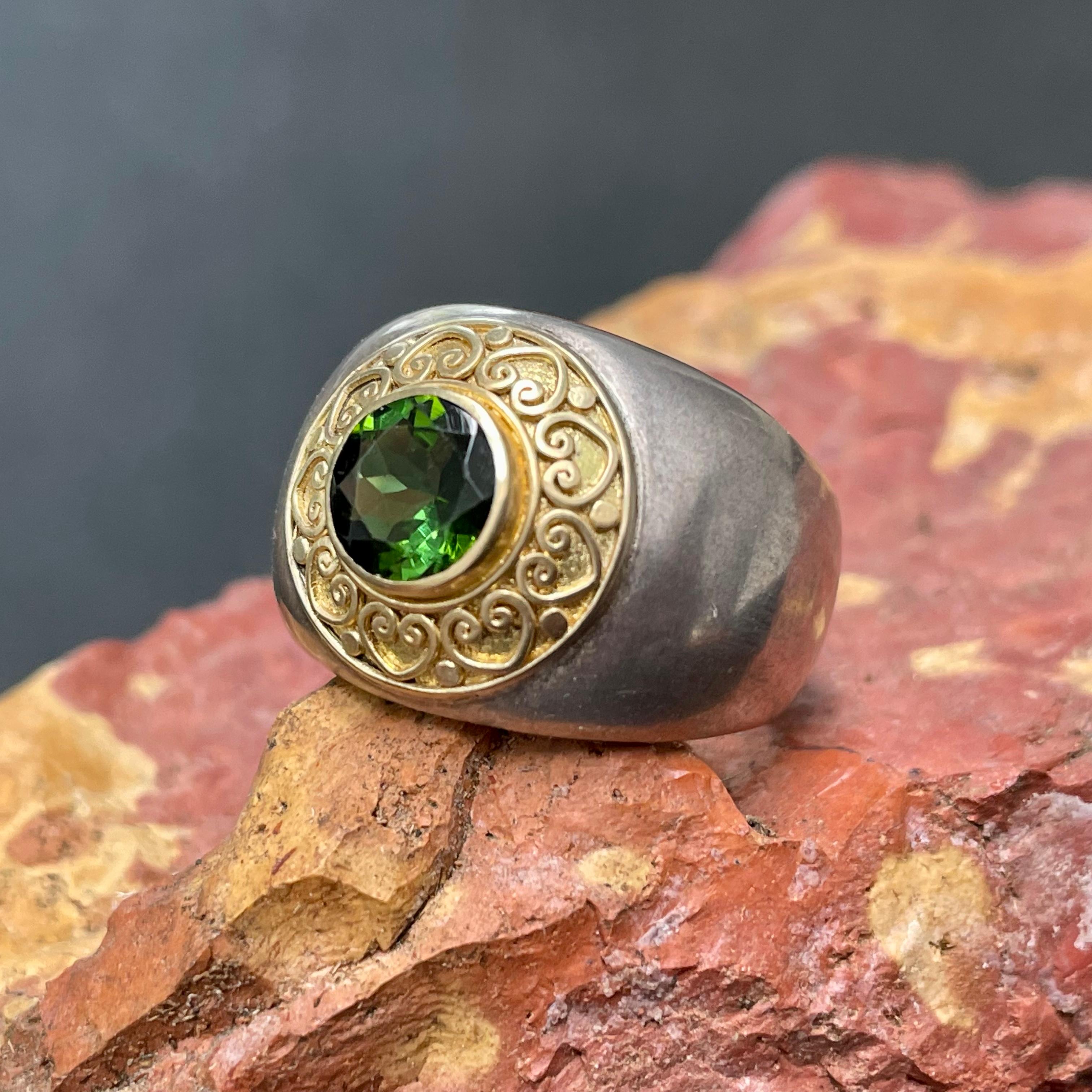 A brilliant round 8 mm faceted green tourmaline is surrounded by intricate handmade 