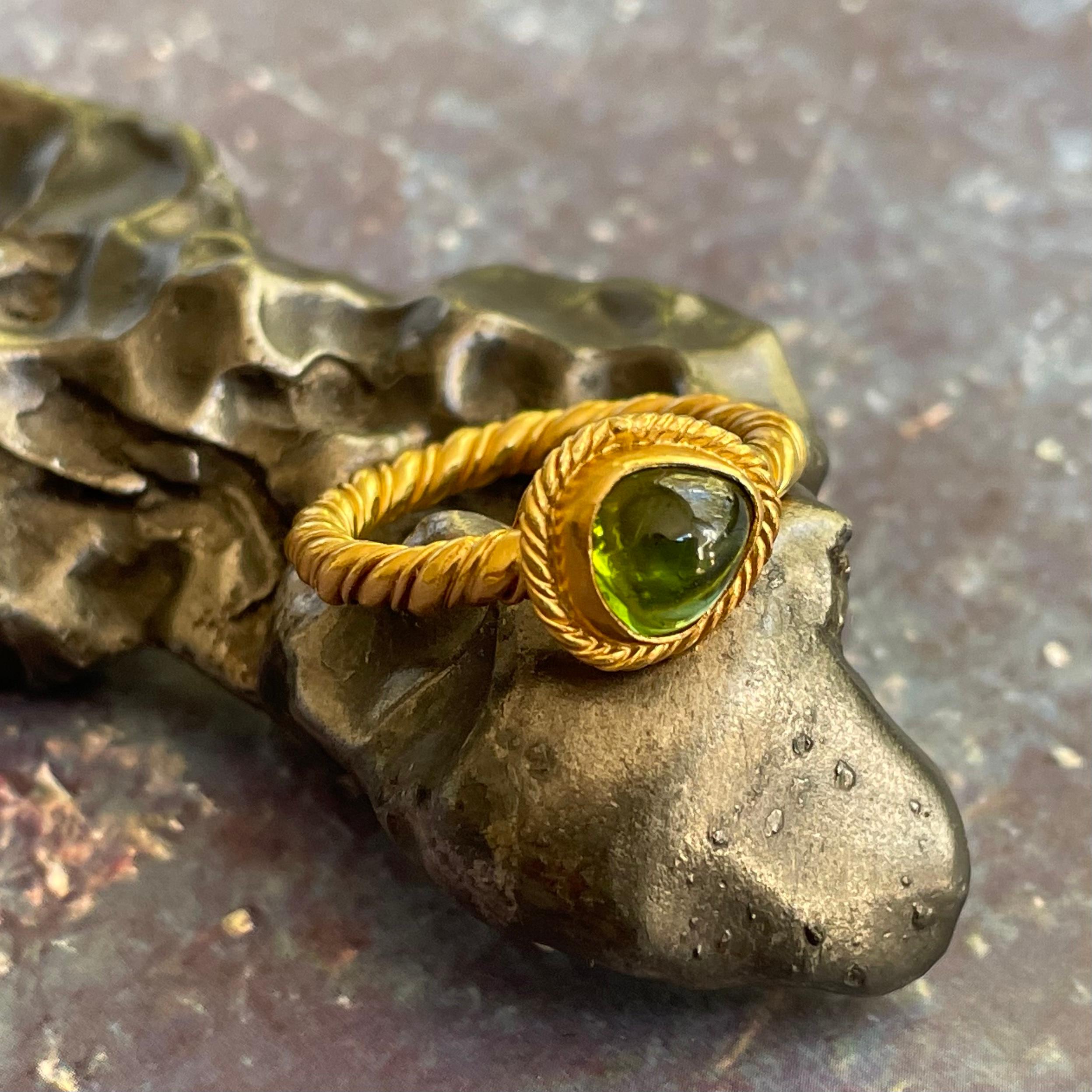 An interesting slightly irregular approximately 6 x 7  mm green tourmaline cabochon is held in a rich 22 carat gold twist wire embrace within a hefty large and small twist wire handmade ancient-inspired shank.  Something out of an Etruscan tomb
