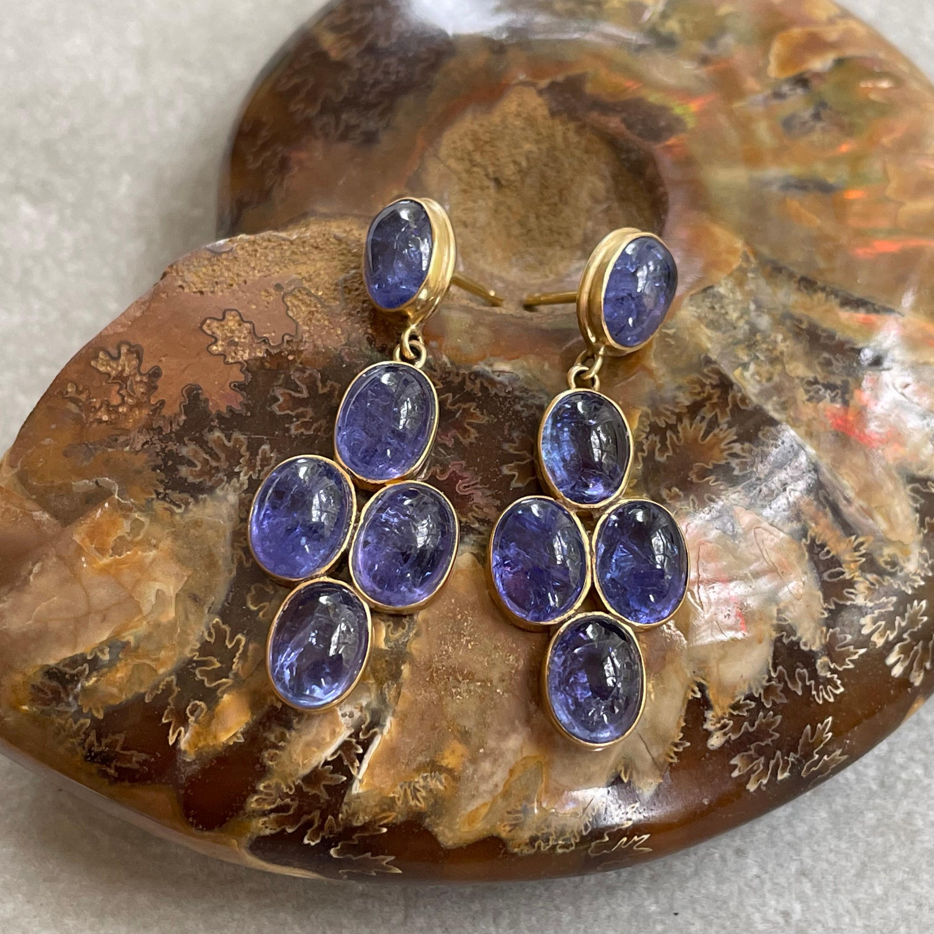 Deep purplish blue 6 x 8 mm oval tanzanite cabochons in a vertical grouping hang below a similar cabochon post in this attractive design. A big splash of color!