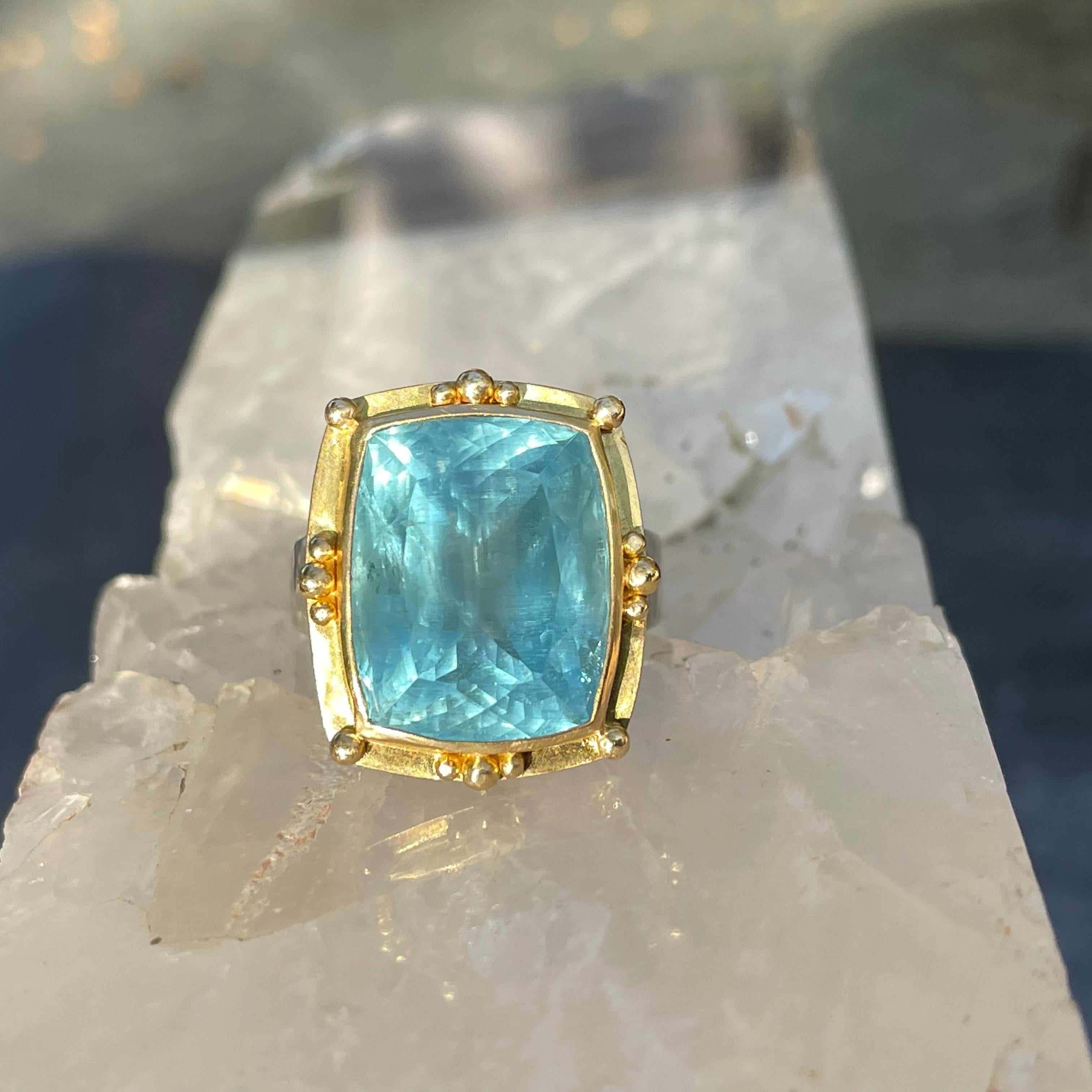 A lively and reflective 13 x 16 mm sightly widened emerald cut aquamarine is set in a medieval-inspired Steven Battelle 