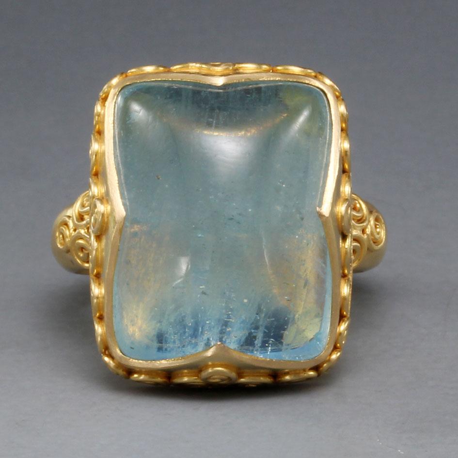 A light, sea-blue 13 x 15 mm cushion shaped  Brazilian aquamarine cabochon is held vertically in a signature 