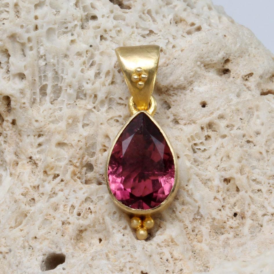 Une tourmaline rose brésilienne facettée en forme de poire de 7 x 10 mm, vive et brillante, est sertie dans une monture au fini mat.  Lunette en 18 carats avec un accent 
