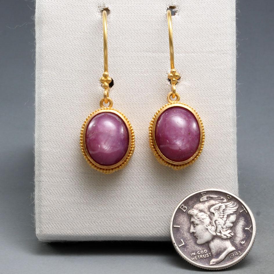 Two well matched Indian 9 x 11 mm cabochon pink star rubies are set in deep 22K gold bezels decorated with intricate hand-set tiny geometric 