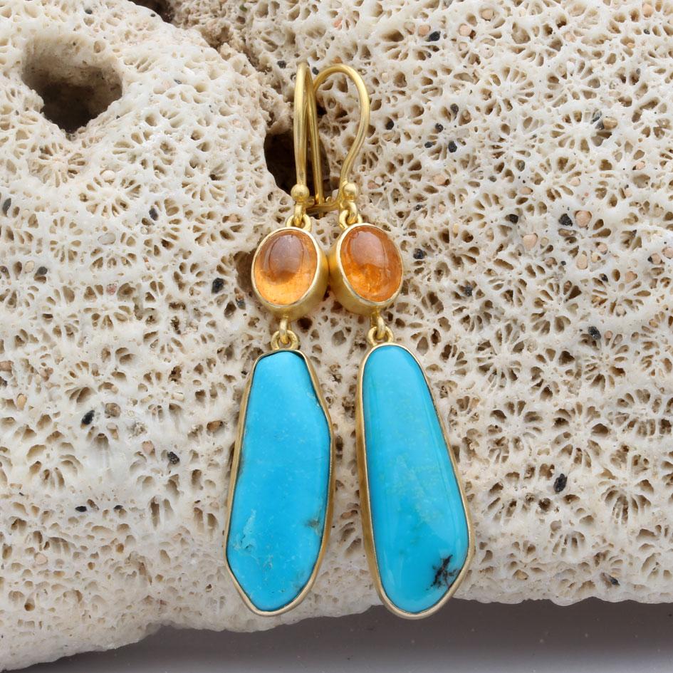 Two slightly irregular 9 x 25 mm cabochons of Arizona Sleeping Beauty mine turquoise dangle below bright orange 5 x7 mm spessartite garnet cabochons in the attractive artisan crafted 18K organic gold earring design.  All suspended below