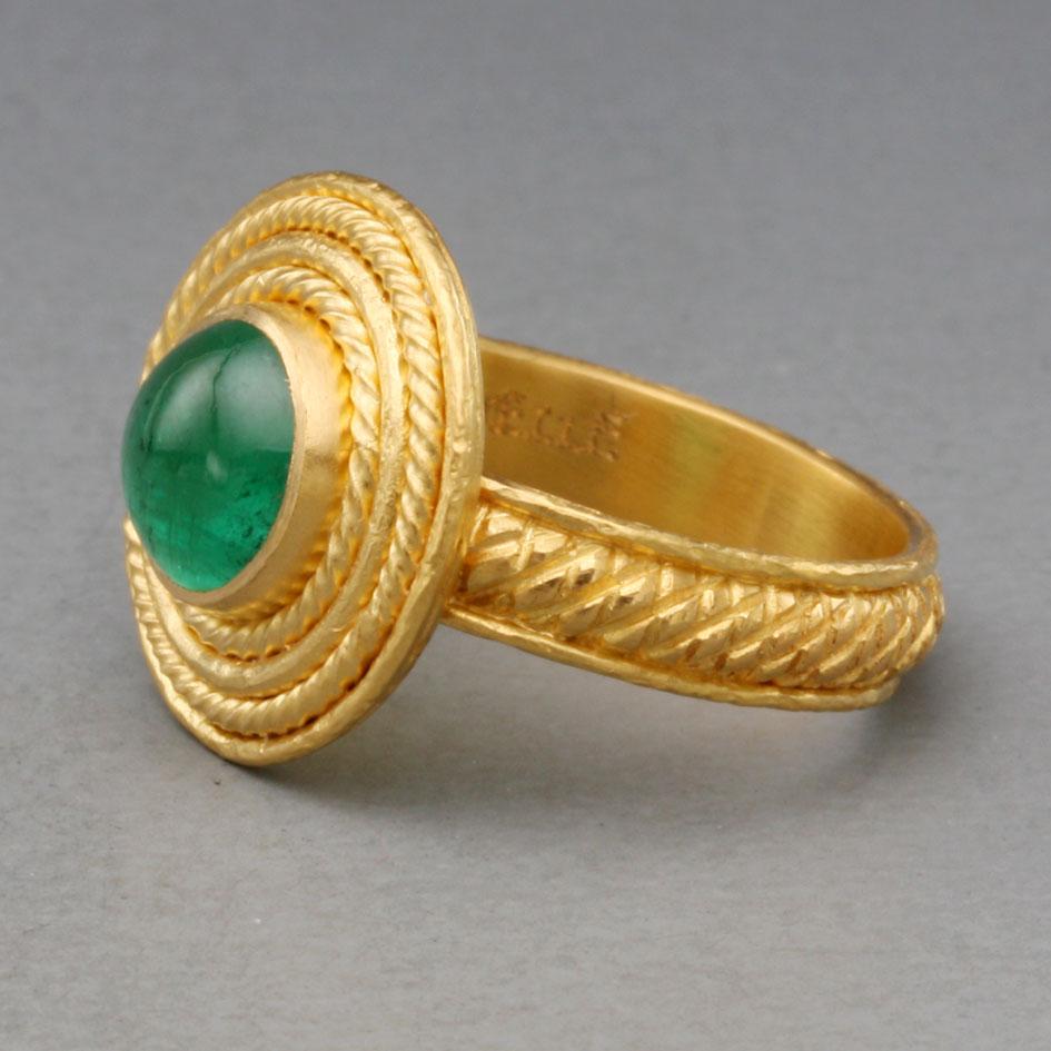 A beautiful 7mm round cabochon emerald is surrounded by concentric twist and straight wire circles in this ancient-inspired Steven Battelle high carat gold design.  The substantial handmade shank is ornamented similarly to complement the bezel. This