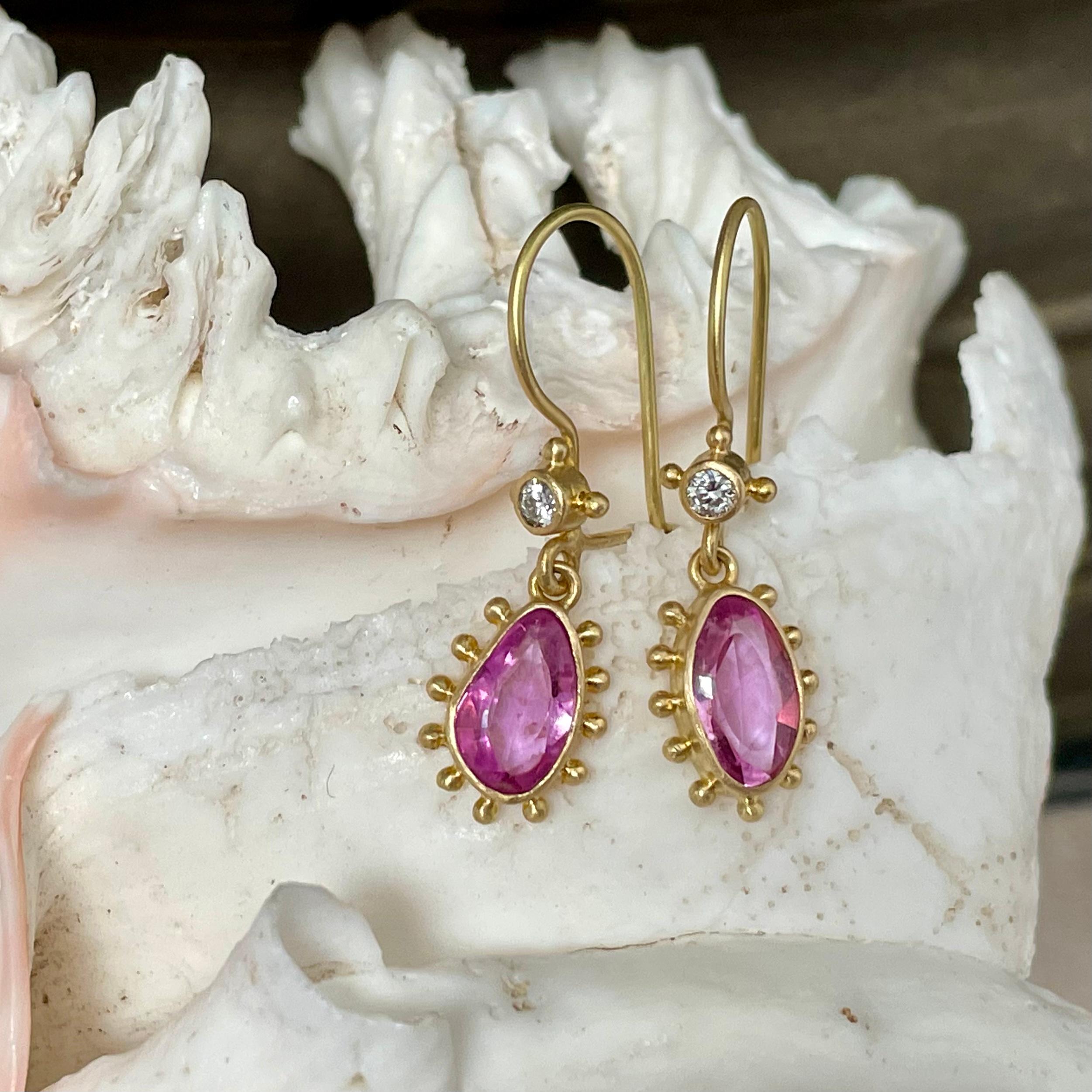Two approximately 7 x 9 mm Irregular buff-top faceted pink sapphires are set in simple 18K bezels with separated 