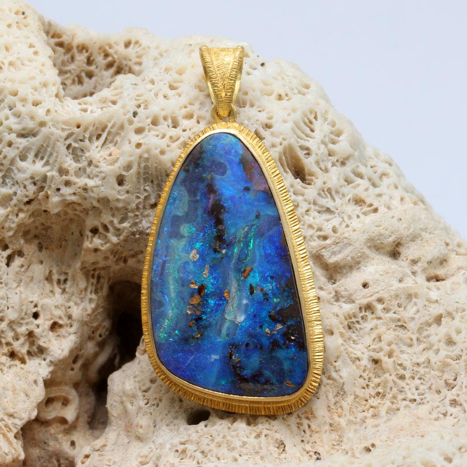 An intricately variegated green and blue 17 x 28 mm semi-pear shaped boulder opal from the Quilpie fields in Queensland, Australia is set in an organic  line textured 18K bezel in this Steven Battelle design.  Amazing colors of the opal contrast