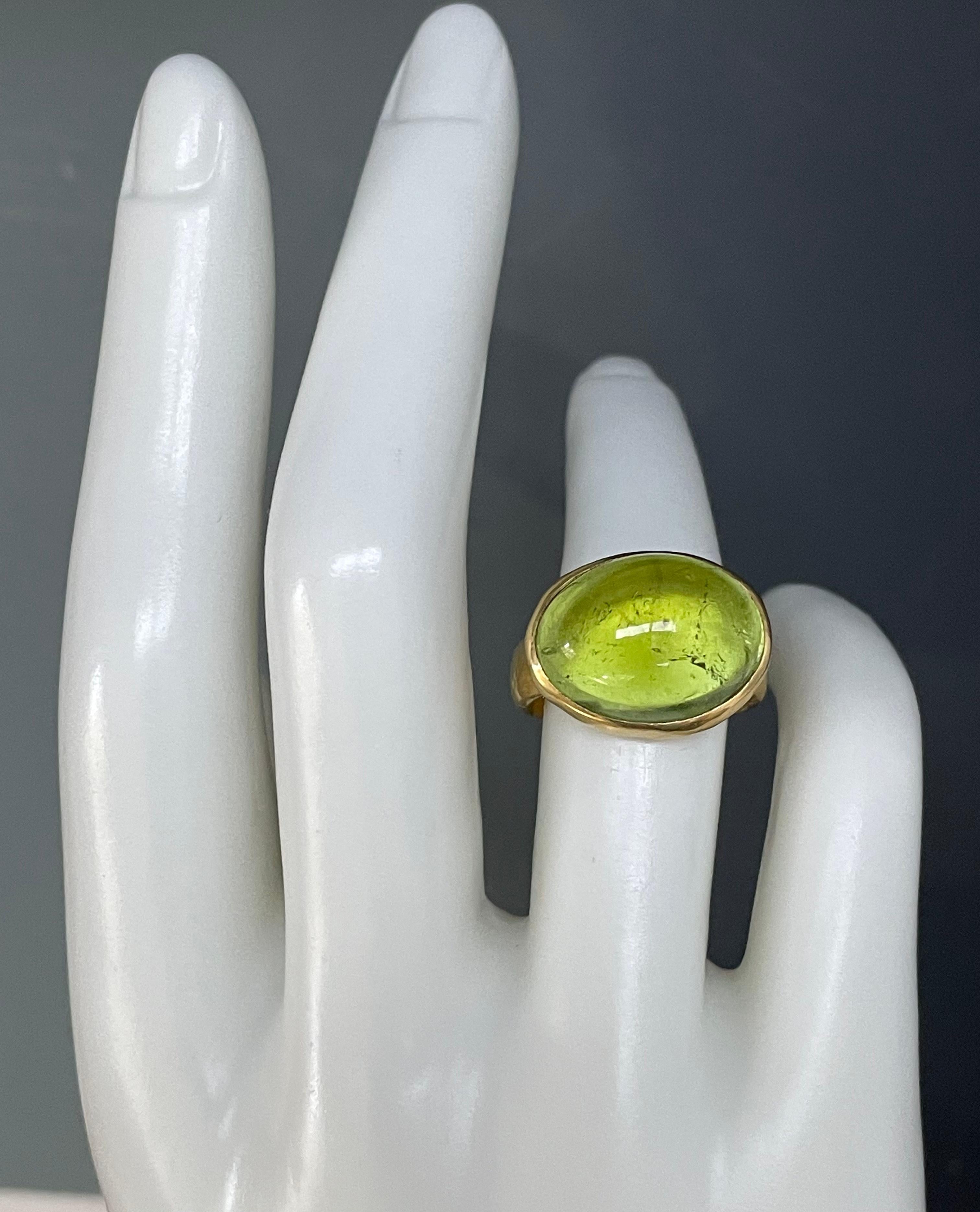 A beautiful, clear, light-ish green 13 x 17 mm oval tourmaline is held in an ultimately simple organic hammered setting and shank in this classic look.  This is a luminous, and juicy, gumdrop of a stone!  Currently sized 6.5.  This ring is