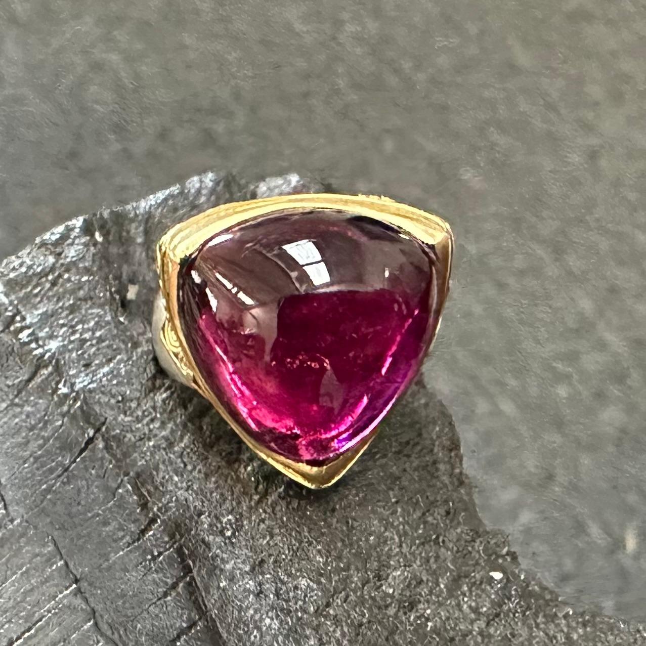 A juicy Brazilian 18 mm trillium cabochon pink tourmaline rests in a cupped handmade 18K bezel accented minimally with delicate 18K wire scroll-work at the corners and continuing on the wide matte-finish sterling shank.  Just enough ornament to