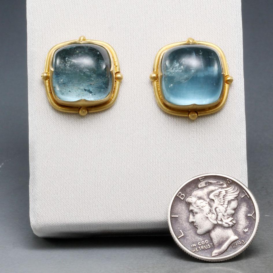 Two matching 12mm cushion shaped Brazilian aquamarine cabochons are set in complementary 
