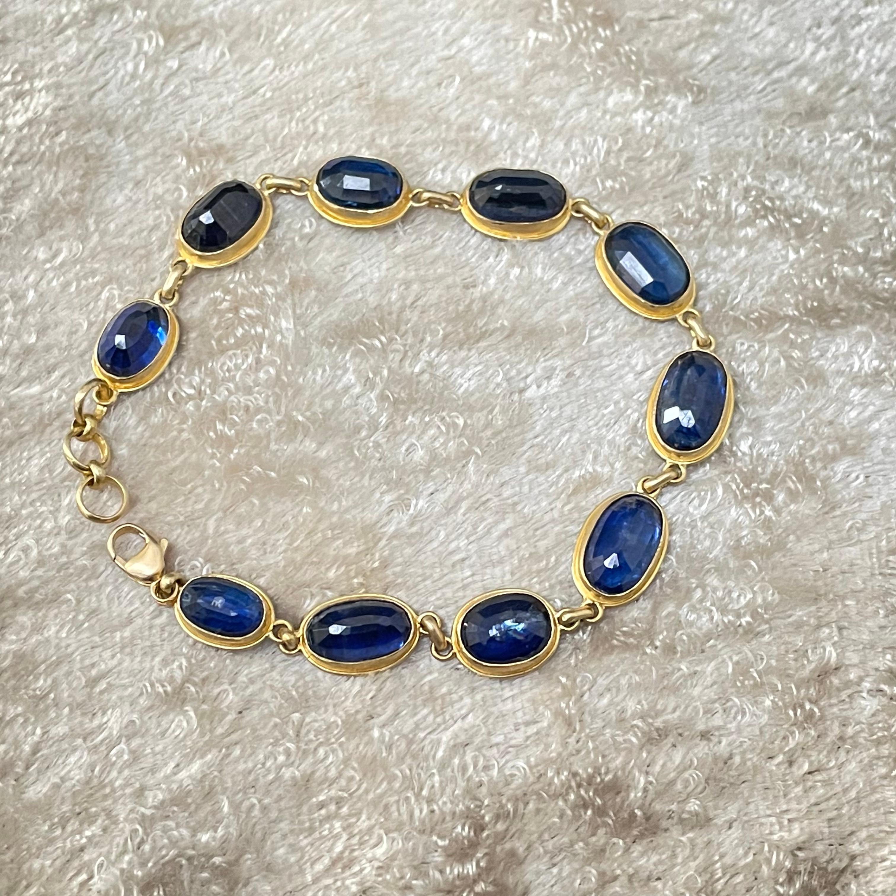 Ten brilliant blue rose cut kyanites from 7 x 9 mm to 8 x 12 mm in size are set in simple matte-finish 18 bezels with surrounding double bezels in this 
lively juxtaposition of blue and gold.  Slightly adjustable at 7 inches, this currently fits