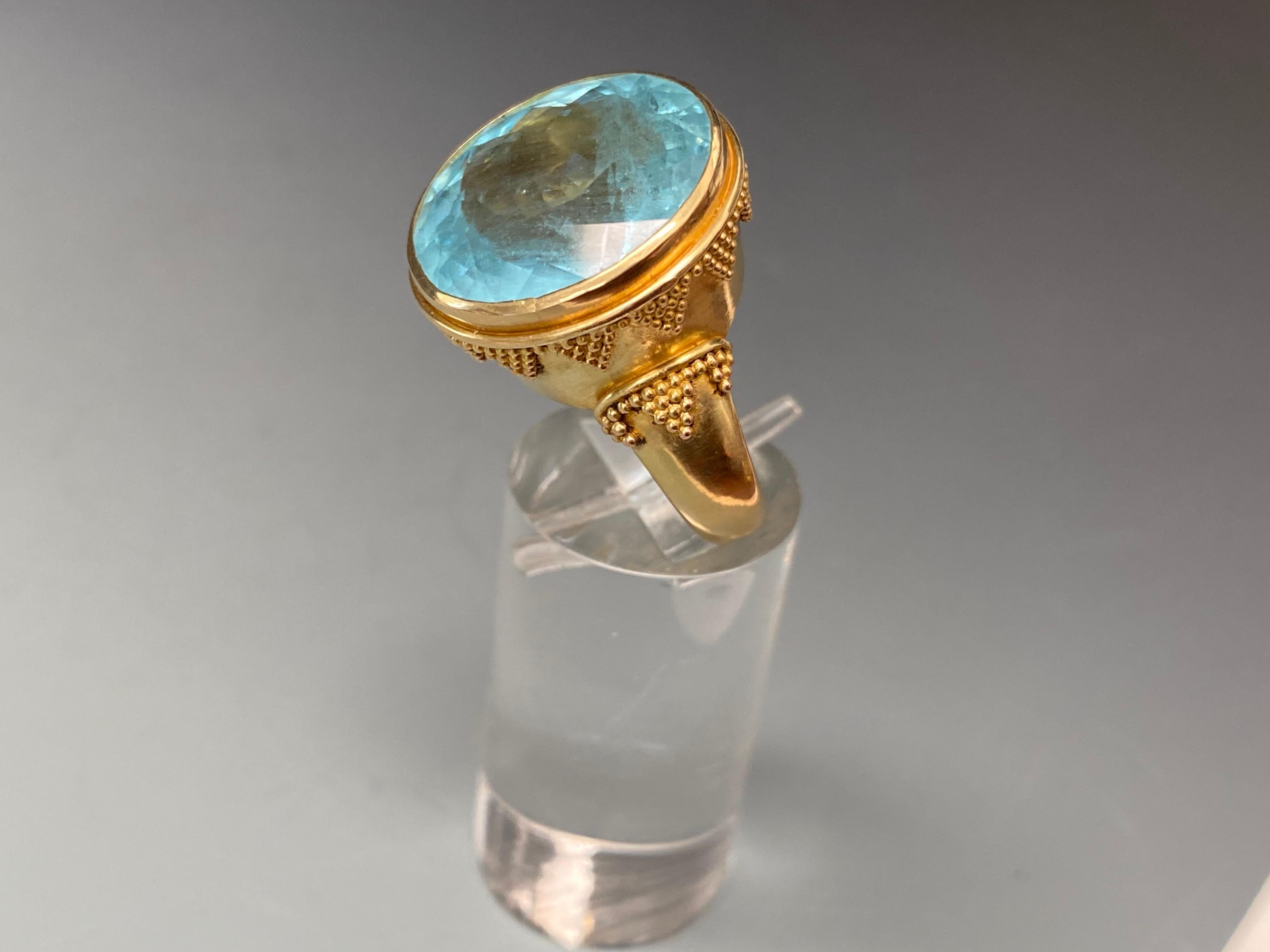 A beautiful round faceted Brazilian aquamarine is held in a 