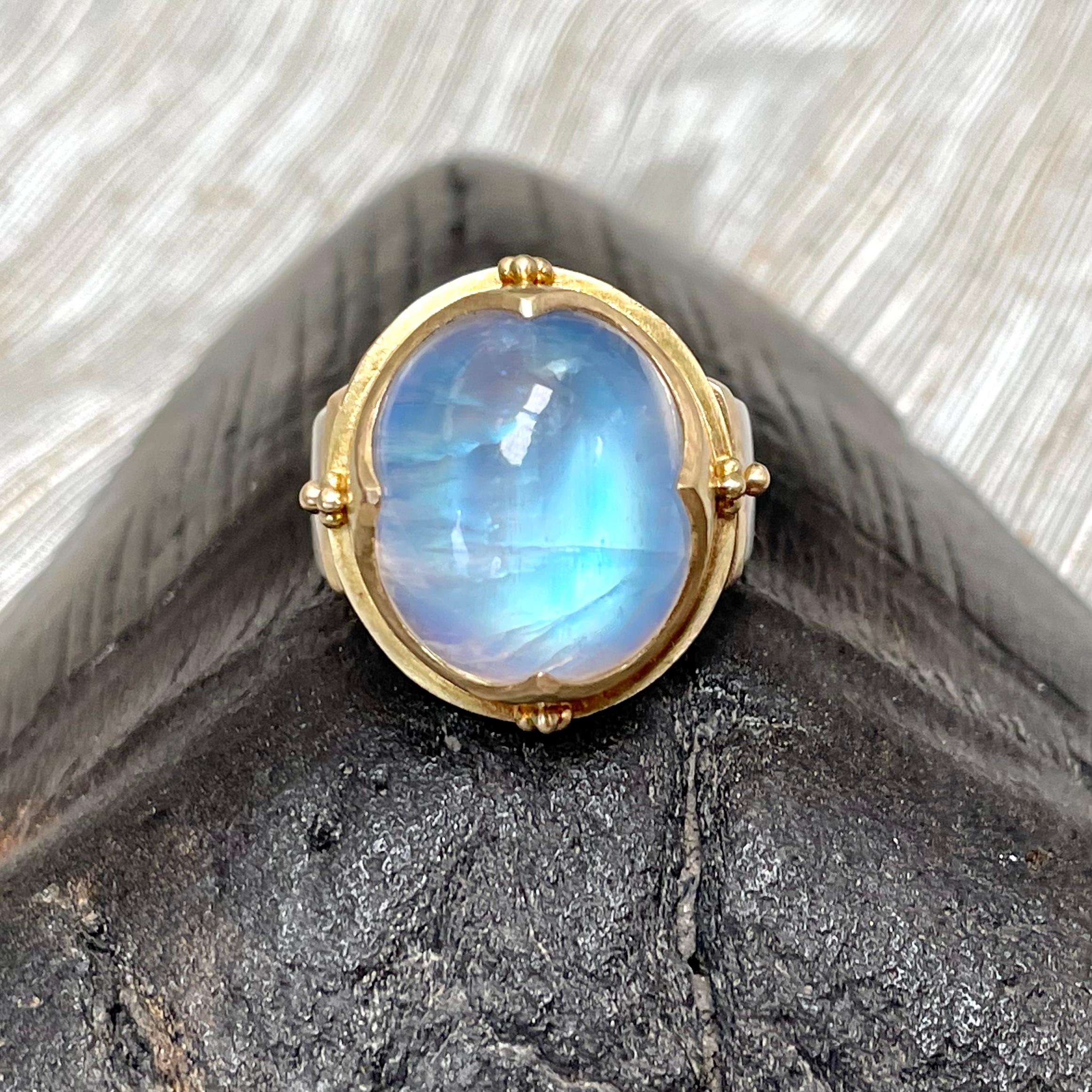 A beautiful blue 15 x 17 mm oval cabochon rainbow moonstone is held in a signature 