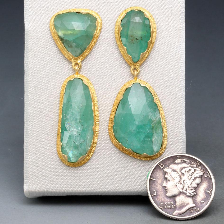 Four irregular shaped rose-cut emeralds sized between 8 x 11 and 13 x 18 mm are surrounded by wavy 18K gold bezels and line textured surrounding double bezels in these green and gold organically shaped beauties.  A very distinctive handmade look
