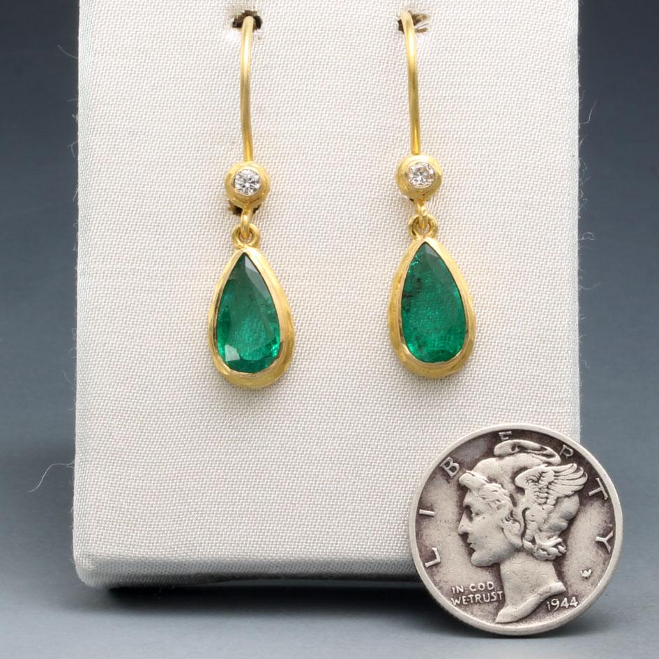 Two bright, lively, and well matched 5 x 10 mm long pear shaped faceted Zambian emeralds are mounted in thick textural 18K gold double bezels and dangle below sparkling 2mm VS1 diamonds on safety-clasp 18K ear wires.  These are sized just right for