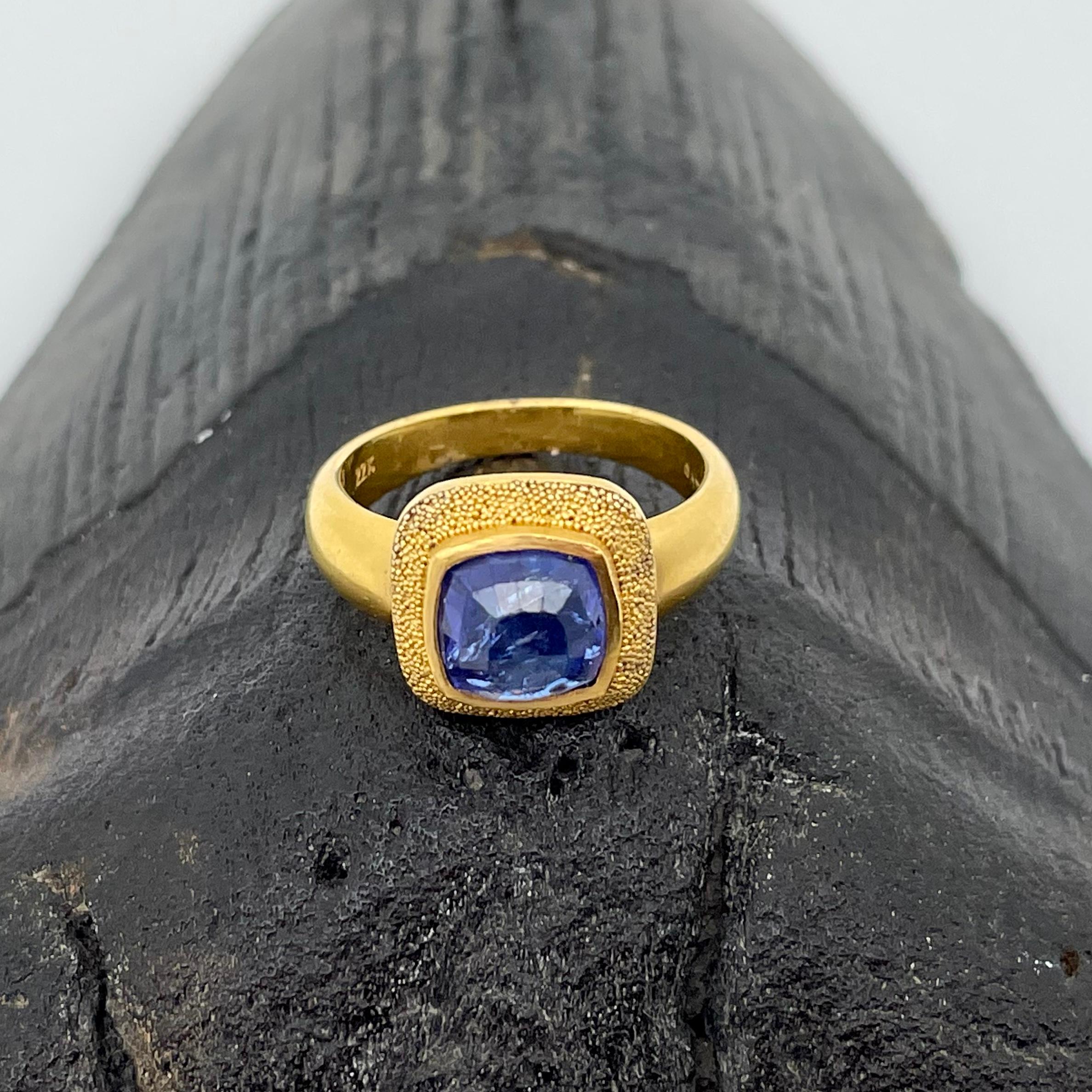 A deep purple-blue high grade rose-cut 7 mm Tanzanite pyramid is spectacular surrounded by rich 