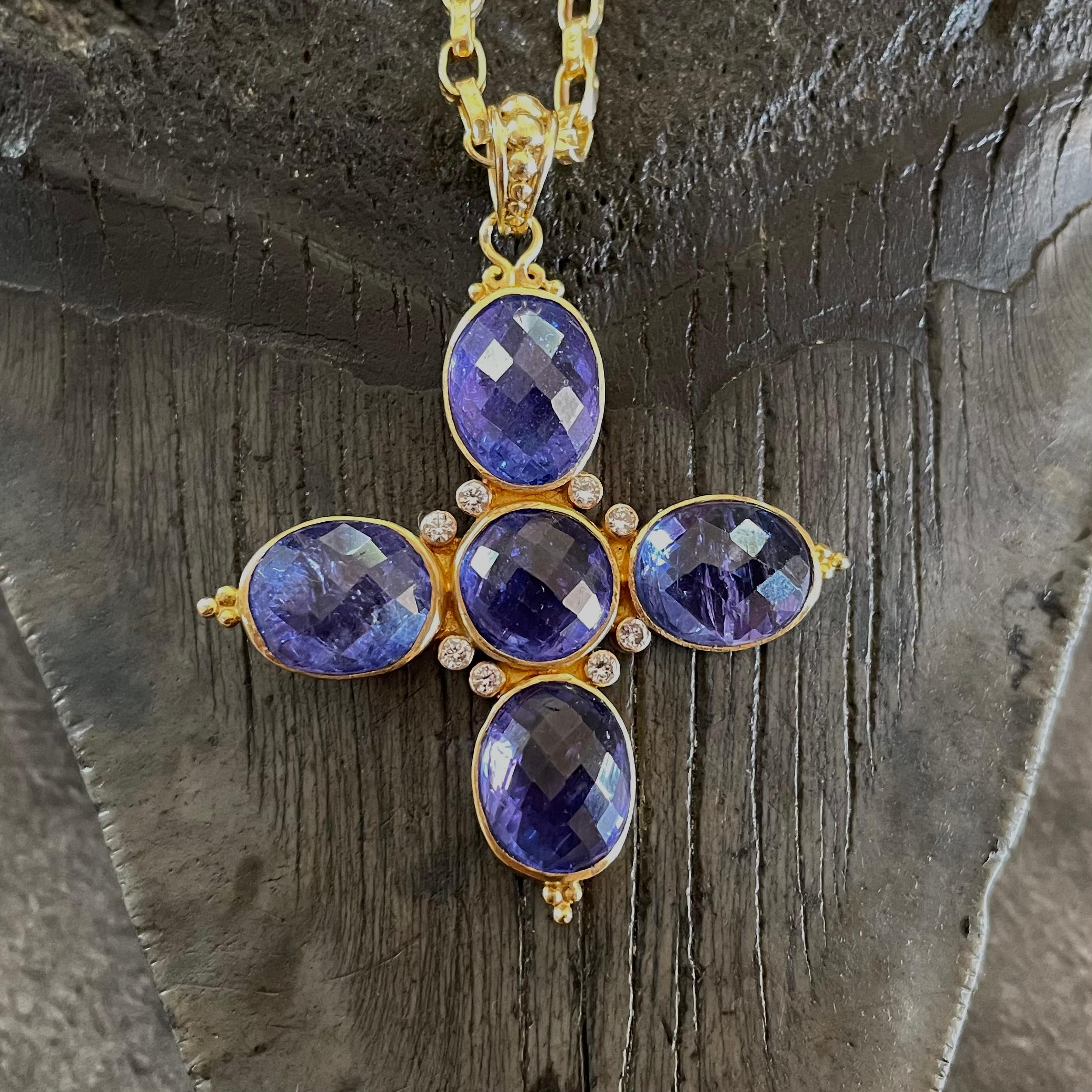 A central 8 mm round rose-cut Tanzanite is surrounded by eight sparkling 1.8mm VS1 diamonds with outstretched 9 x 11 mm oval Tanzanites extending out into a cross.  Granulated 