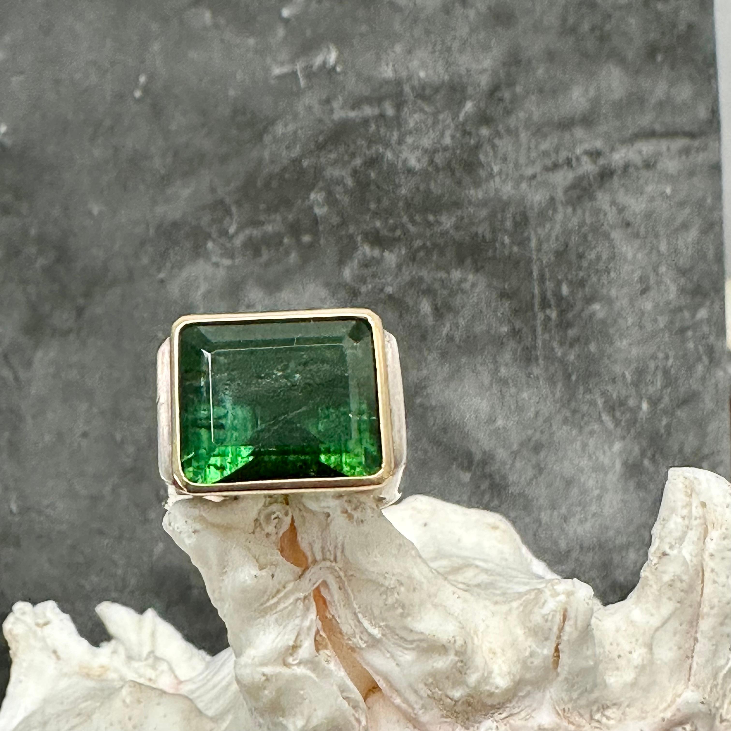 An octagonally cut Brazilian green tourmaline is displayed in an 18K gold 