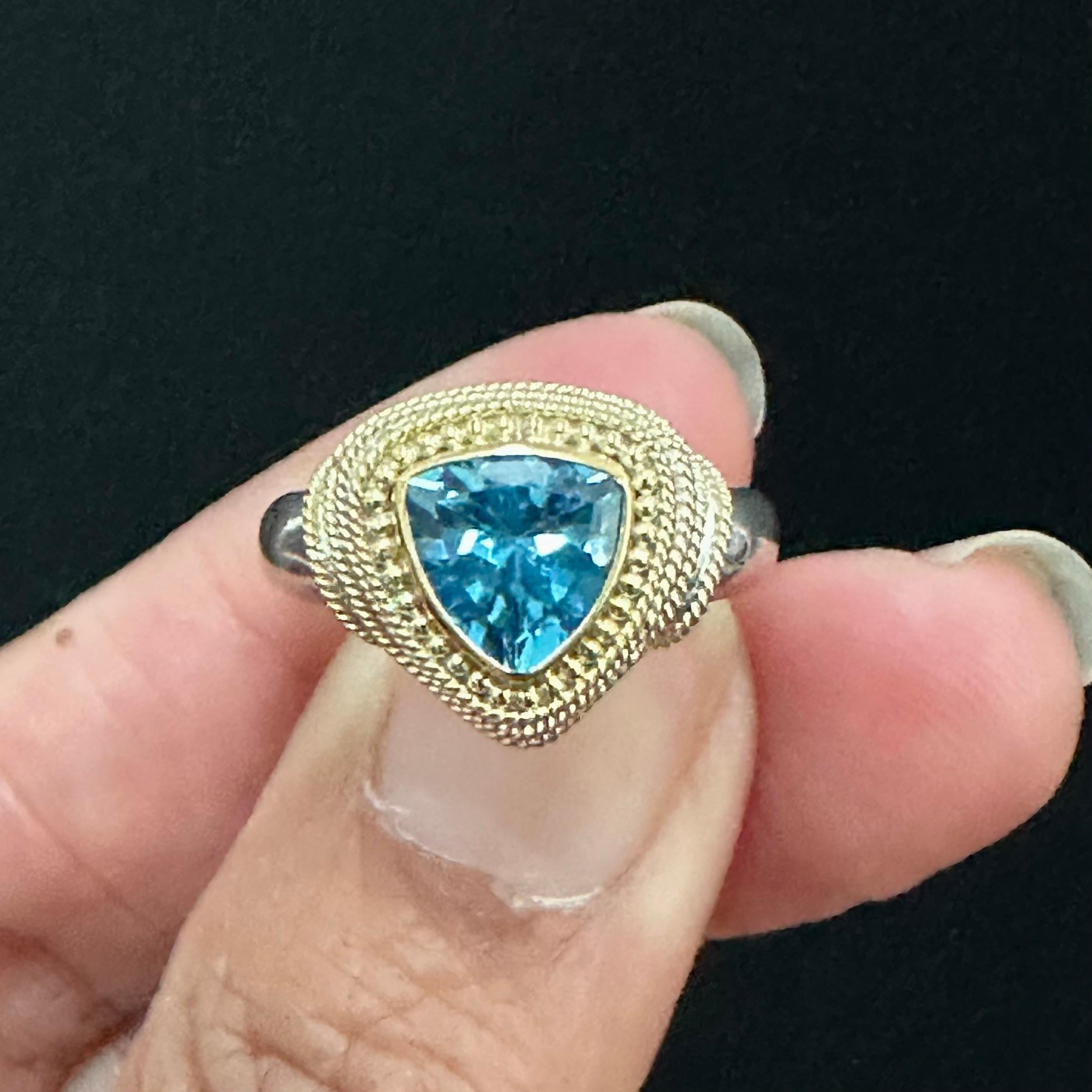 A sparkling 8 mm trillium faceted deep blue topaz is surrounded by handset 