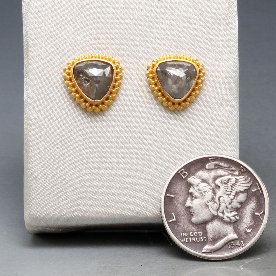 Two 7 mm trillium rose faceted grey diamonds rest in granulated high Karat gold settings surround by double row 