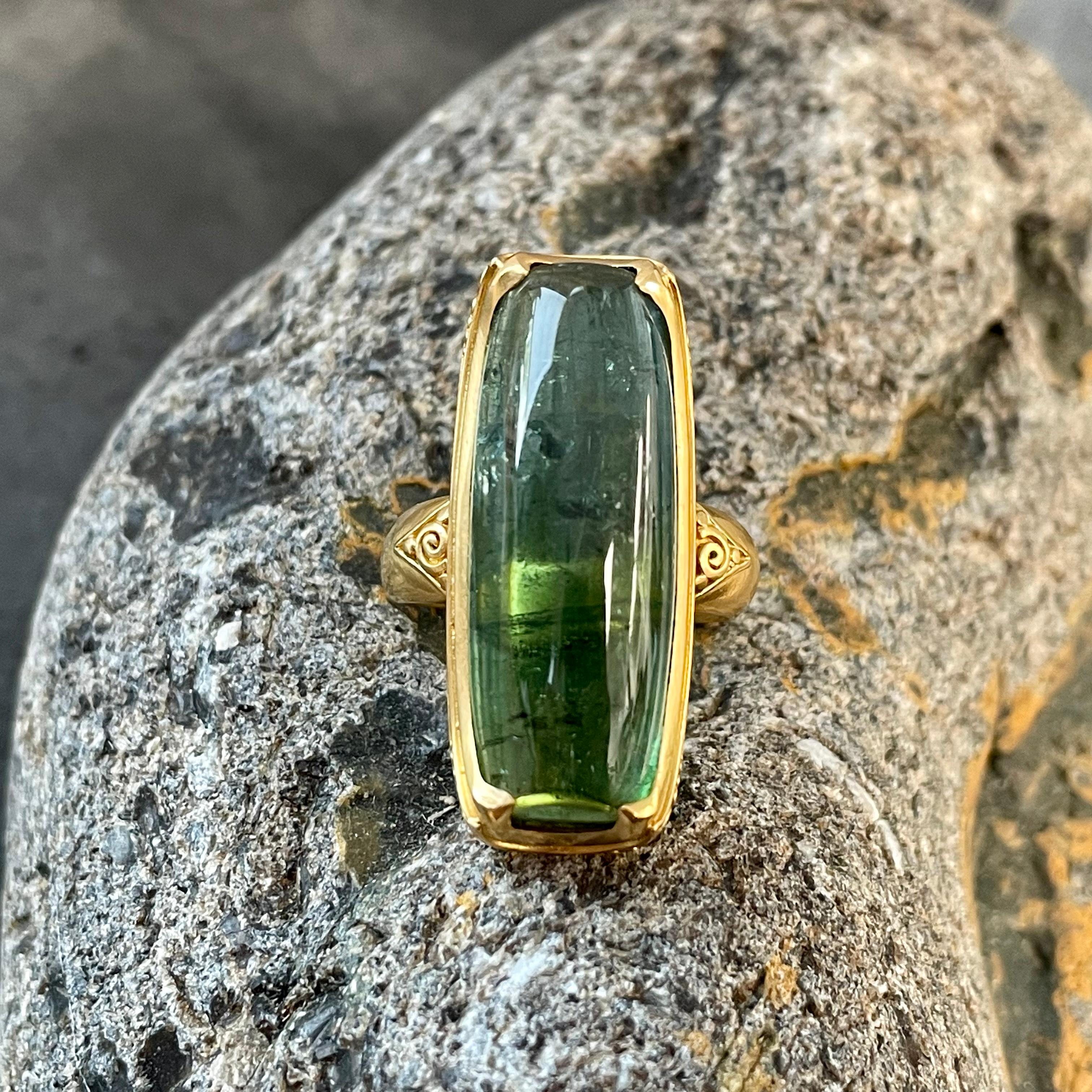 A beautiful long cushion shaped green tourmaline cabochon from Brazil is set in a 
