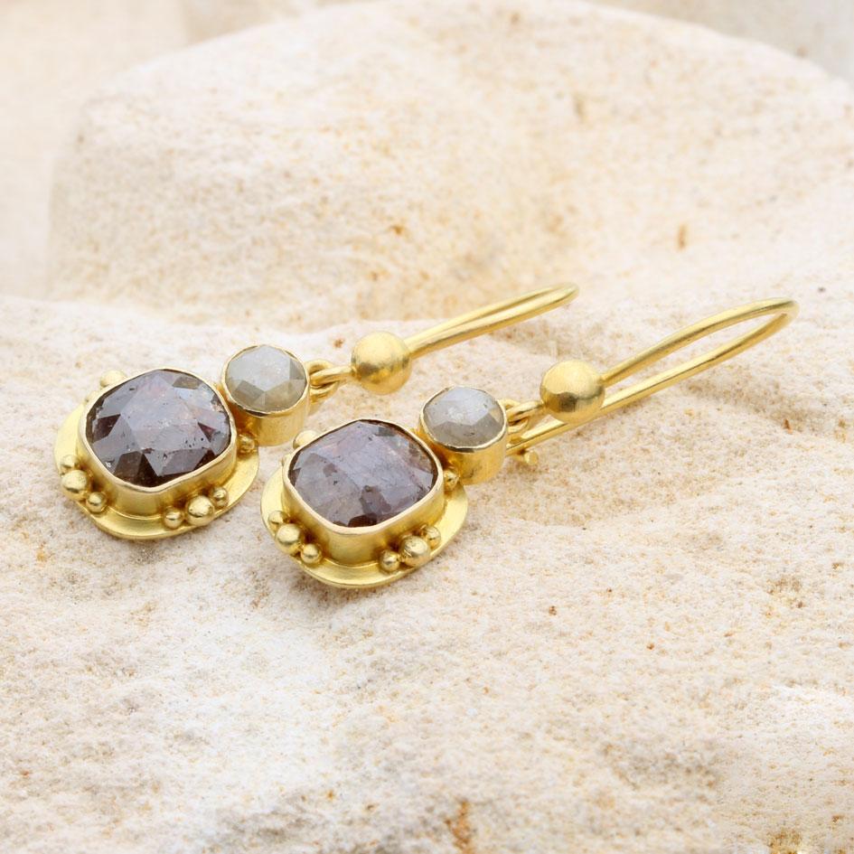 Un diamant brun à facettes coussin de 6 x 8 mm est entouré d'un large double chaton en or 18 carats orné de 