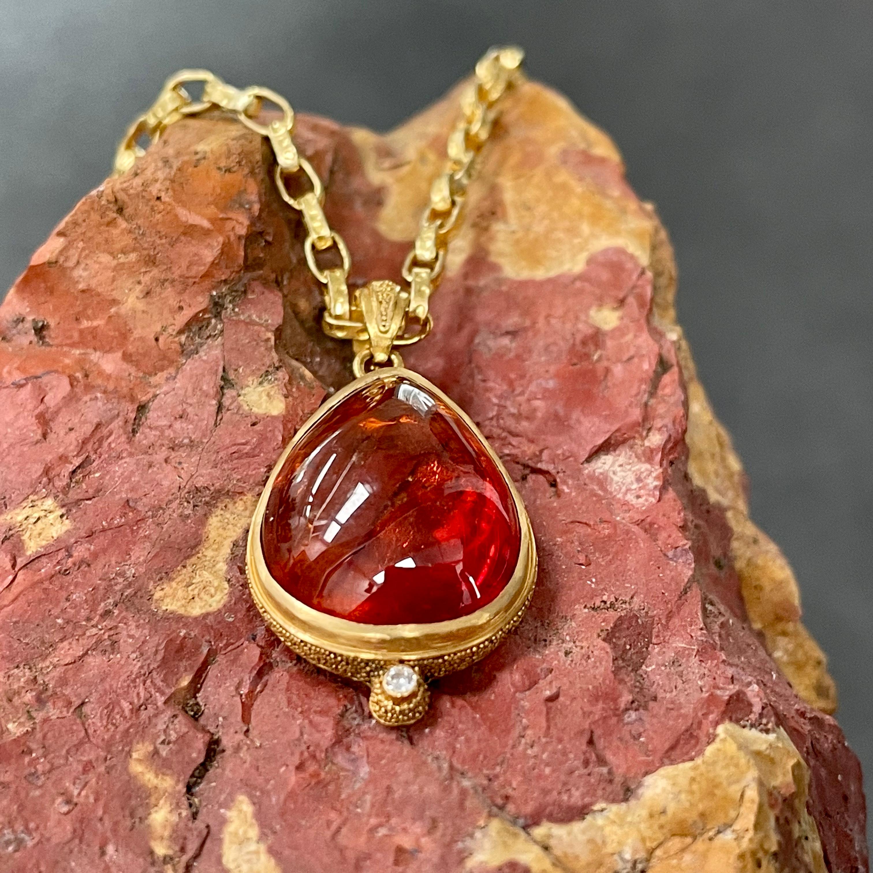 A rich orange-red 14 x 18 mm pear shaped spessartite garnet cabochon is set with fine gold 