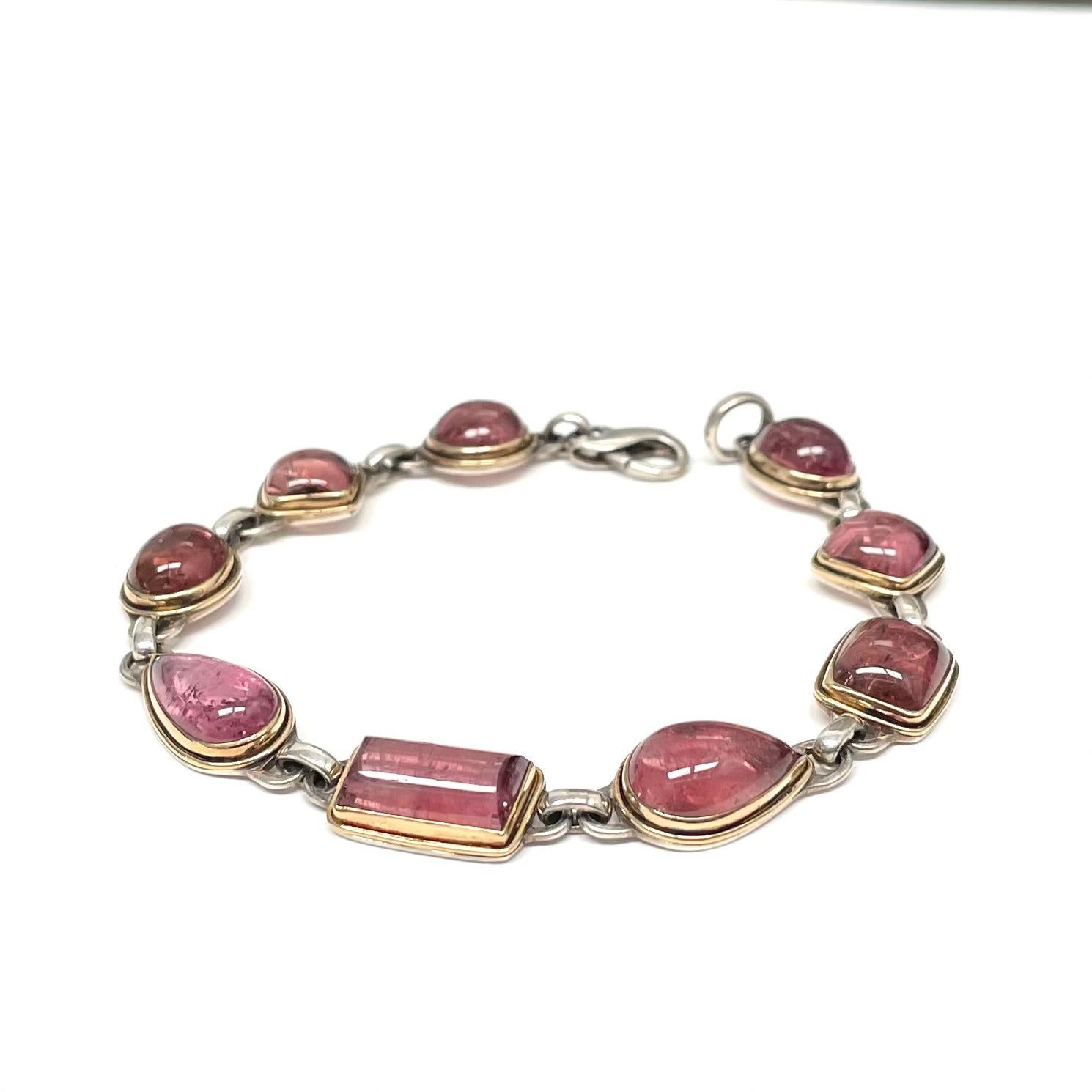 Nine variable shaped approximately 7 x 10 to 9 x 12 mm Mozambique pink tourmaline cabochons are set in 18K gold bezels with surrounding 18K gold wire accents atop sterling silver bases and links in this organic Steven Battelle design.  7.5 inch