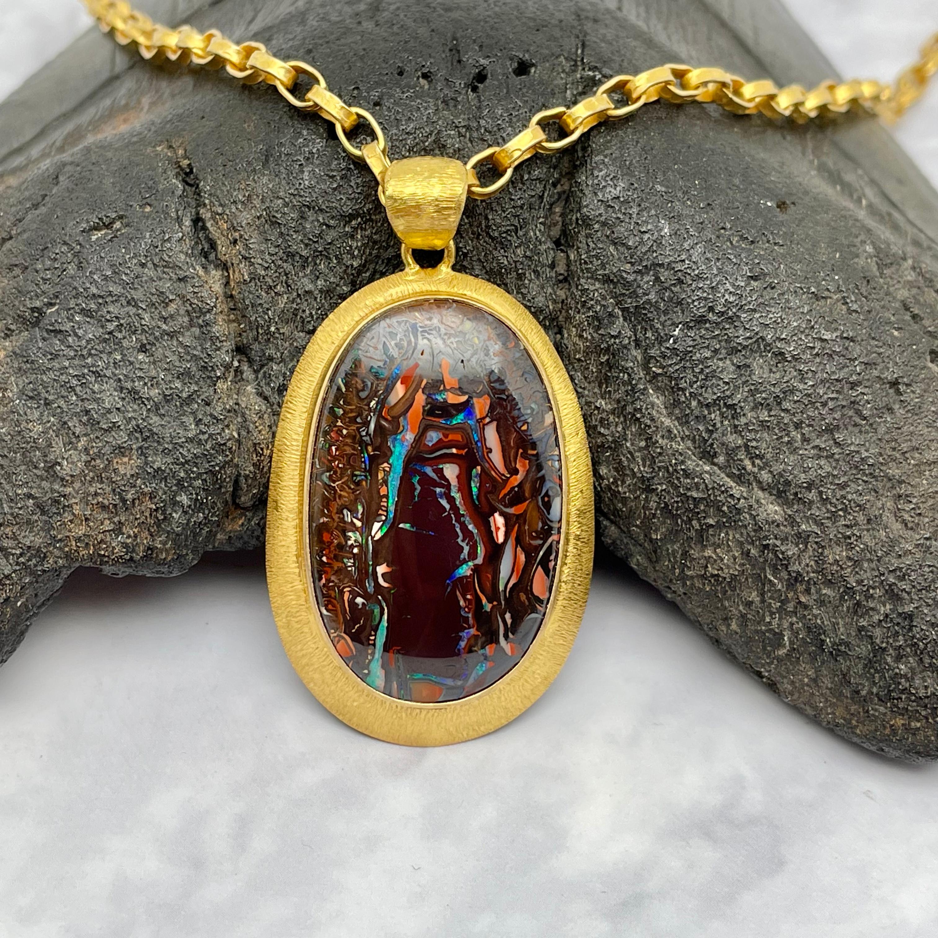 Un bell'opale arlecchino Koroit boulder ovale di 18 x 29 mm, con quasi tutti i colori dell'arcobaleno, è messo in risalto da un'incastonatura a mano in oro 18 carati a doppia linea con un'ampia cauzione.  L'opale di Koroit proviene da un'area