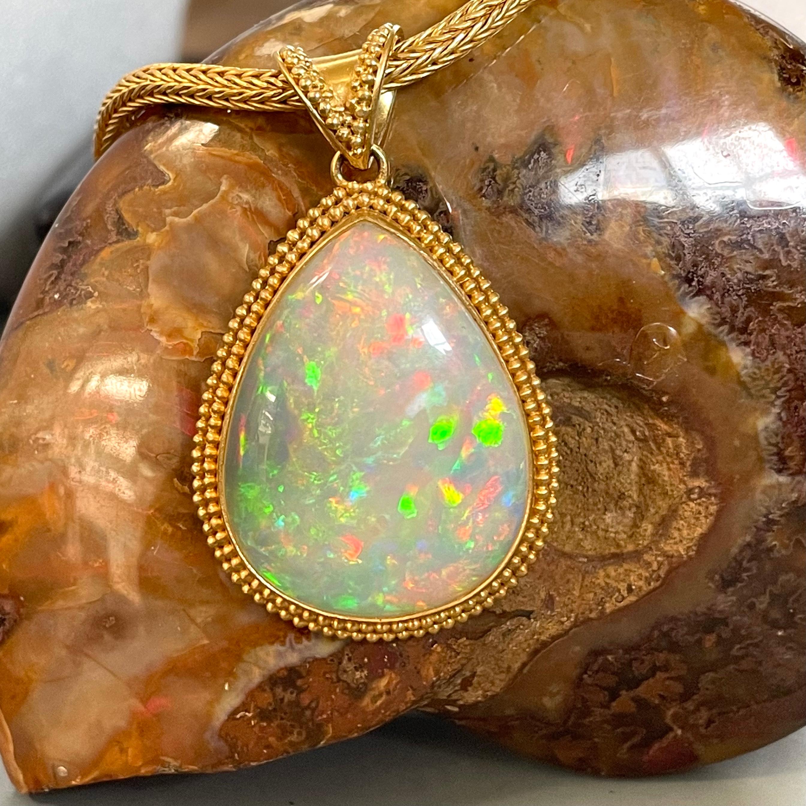 A large, high grade 25 x 32 mm pear shaped opal cabochon is surrounded by a double row of  hand applied 