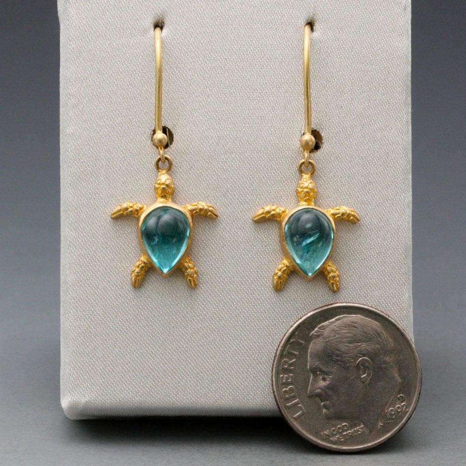 A whimsical wax-carved 18K gold sea turtle is adorned with 6 x 8 mm pear shaped Apaitite cabochons in this Steven Battelle creation.  Mounted on safety clasp wires, these little turtles are sure to delight.