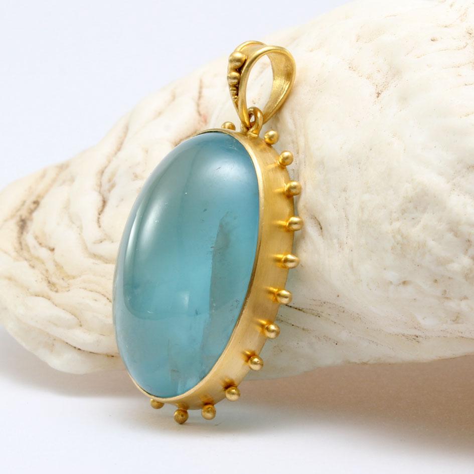 An impressive 18 x 24 mm oval aquamarine cabochon is set in matte-finish handmade 18K gold with radiating large 