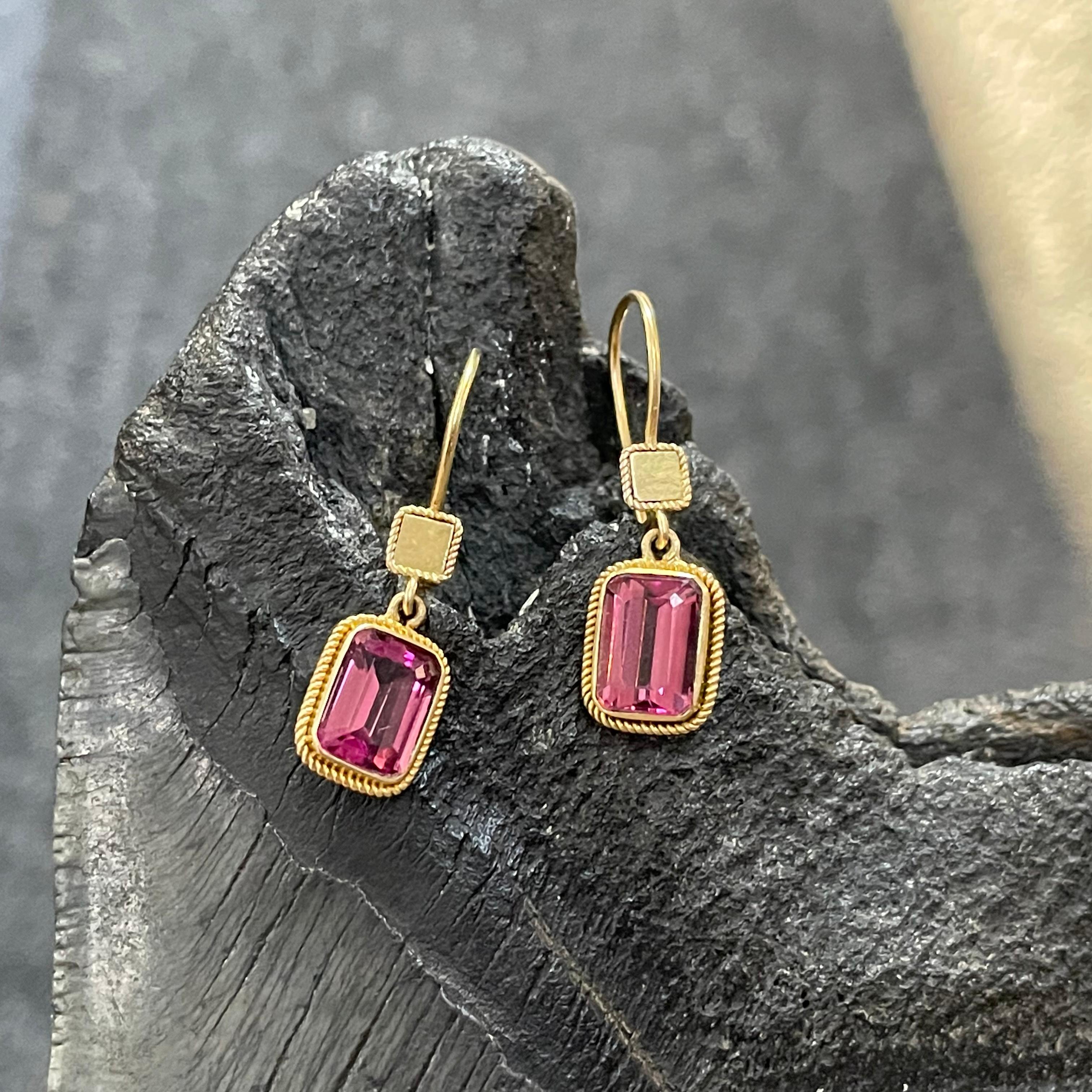 Two bright pink 6 x 8 mm octagonal cut tourmalines surrounded by twist wire accents dangle below similarly ornamented gold squares in this simple yet elegant design. Safety clasp wires.