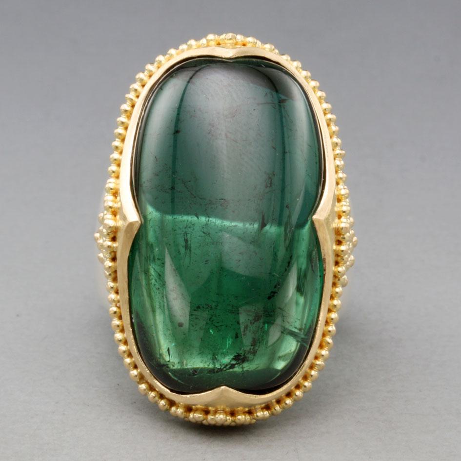 An impressive 16 x 28 mm semi-cushion shaped Brazilian green tourmaline rests within a signature medieval-inspired 