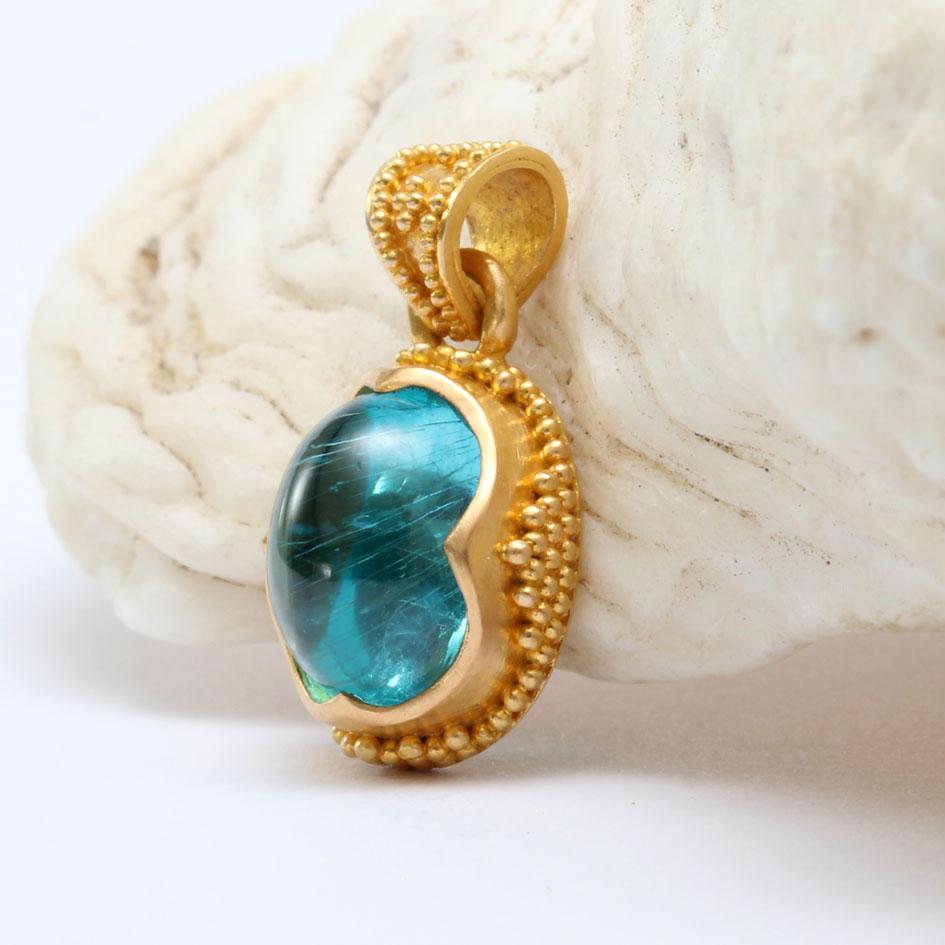 Un vivace e luminoso cabochon di apatite blu mare di 7 x 9 mm è circondato da oro 22 carati riccamente incrostato in questo design di ispirazione antica realizzato a mano da uno dei nostri maestri orafi artigianali. I granuli (chiamati 