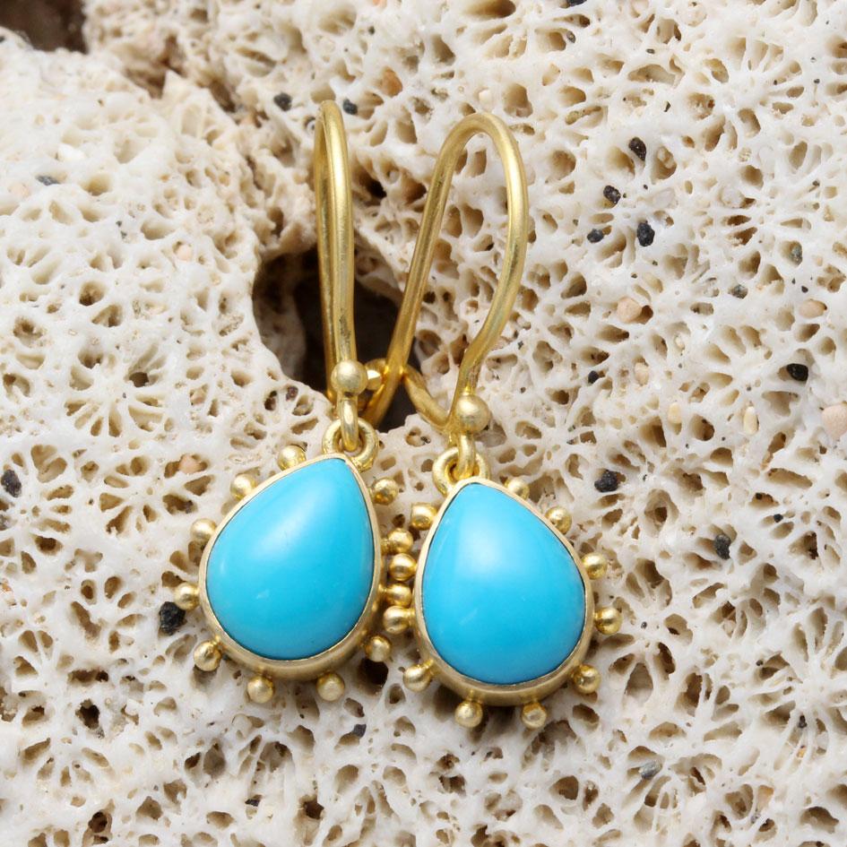 Two 7 x 9 mm flawless Arizona Sleeping Beauty mine turquoise pear shaped cabochons are set in simple matte-finish bezels and surrounded by spaced 