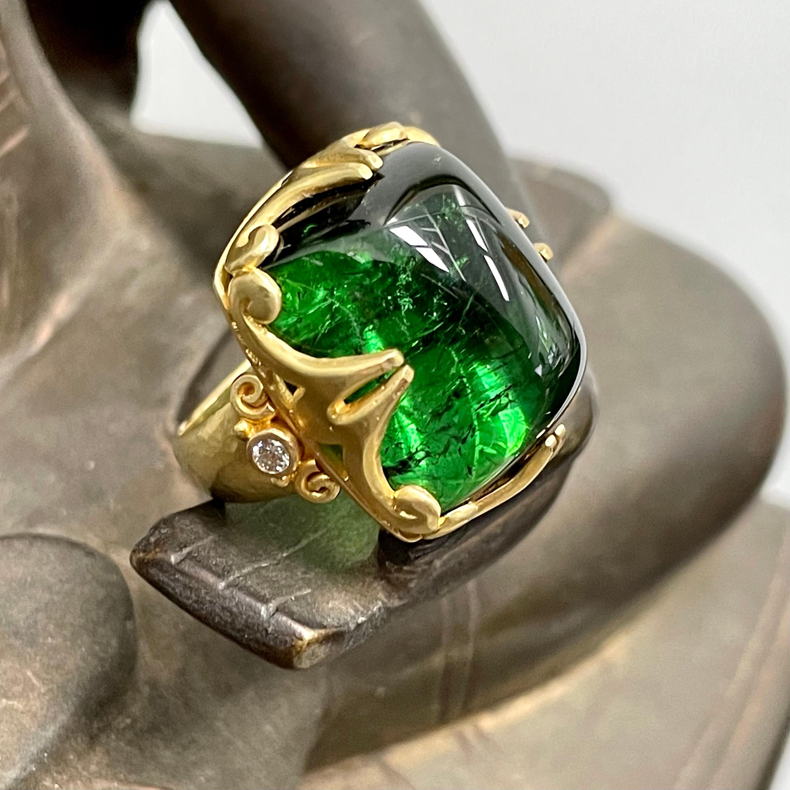 A brilliant Brazilian 16 x 19 mm cushion shaped green tourmaline cabochon is held lovingly in a carved double side prongs with spirals setting, atop a comfortable hammered matte-finish graduated band.  Two 2 mm VS1 side diamonds accent. This gumdrop