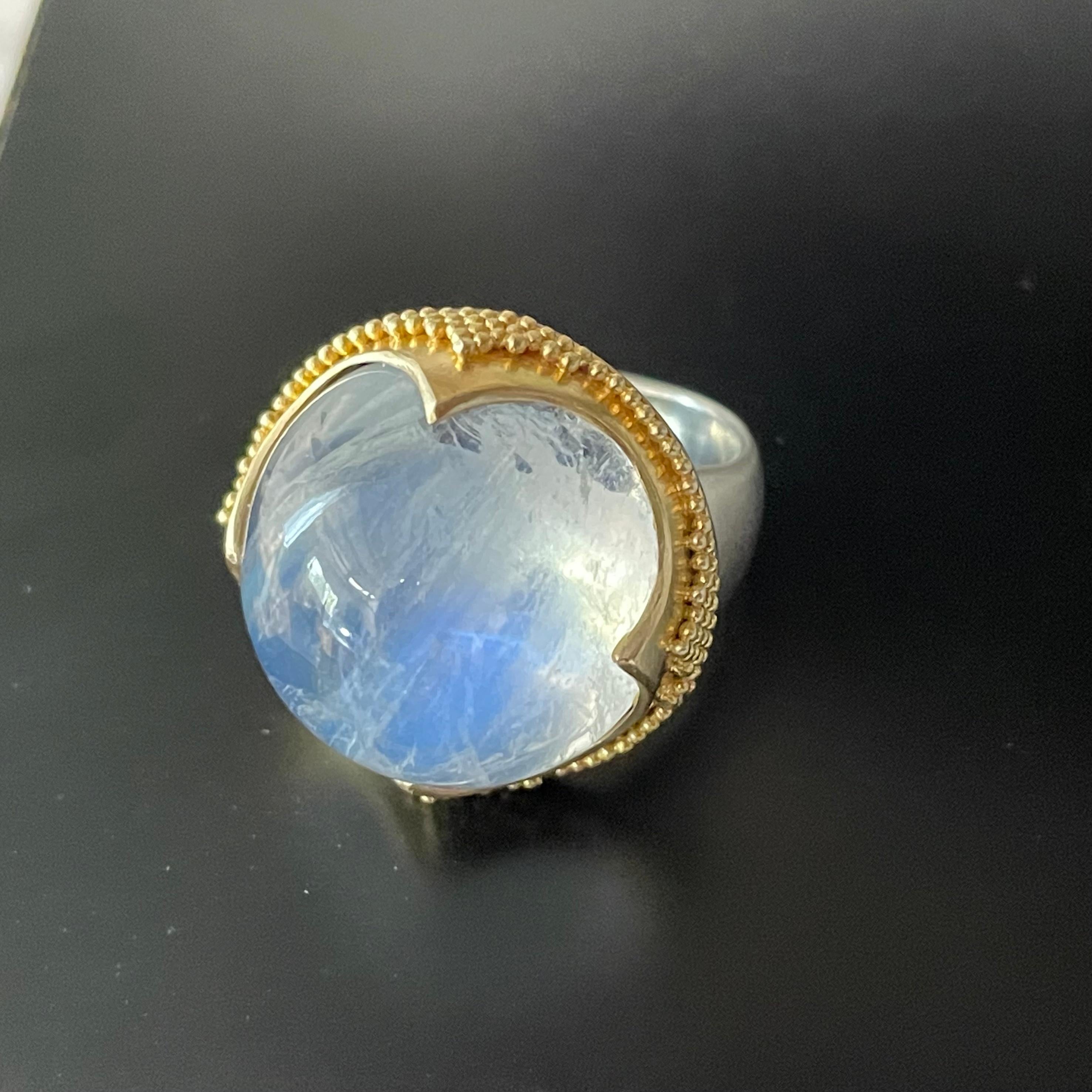 A large 20 mm round cabochon of rainbow moonstone is set in in an ancient inspired 
