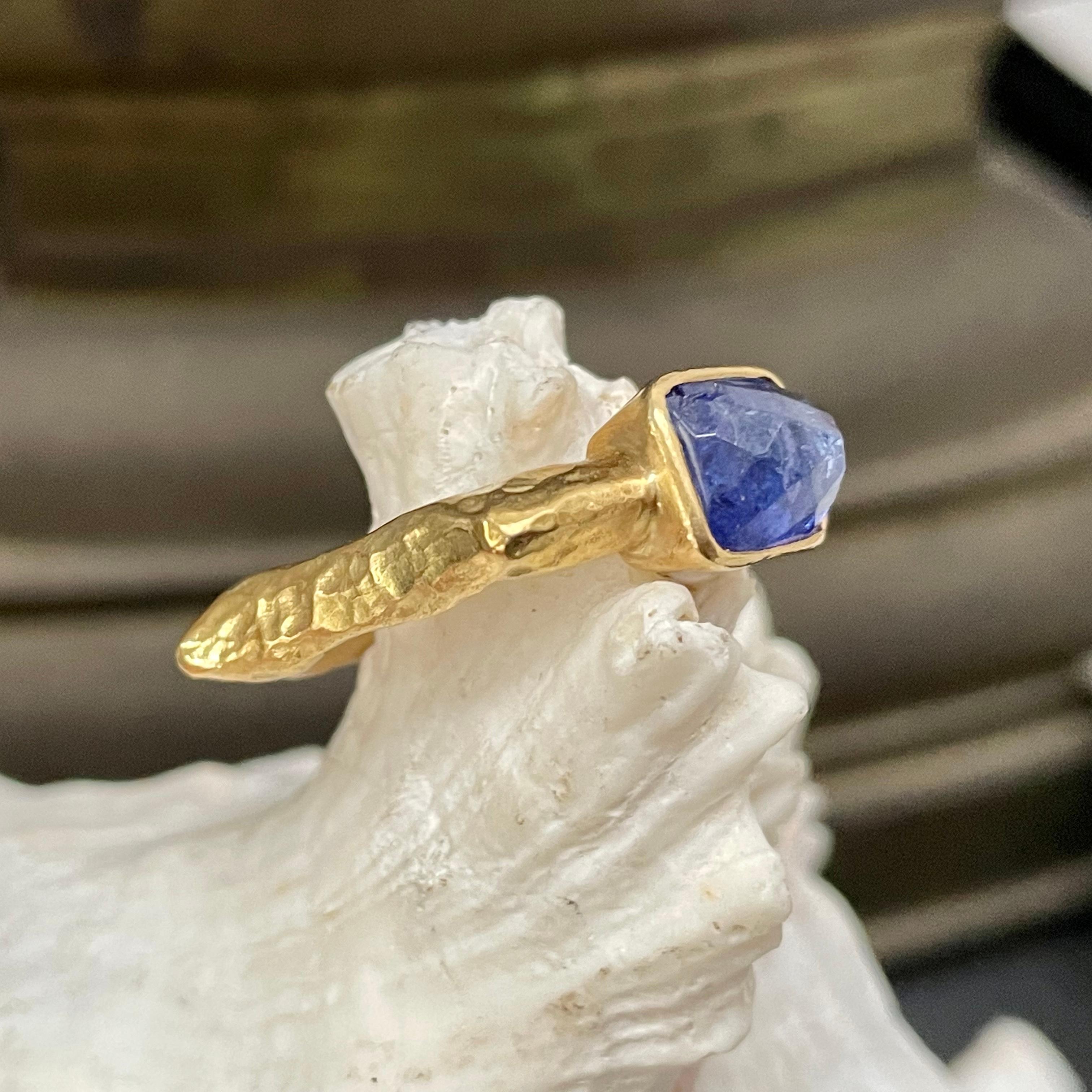 A rectangular 8 x 10 mm rose cut tanzanite is held in a simple hammered bezel atop a shaped heavy gold shank (12.9 grams) that tapers between the fingers for comfortable wearing. A deeply hammered matte-finish is applied to create a look that might