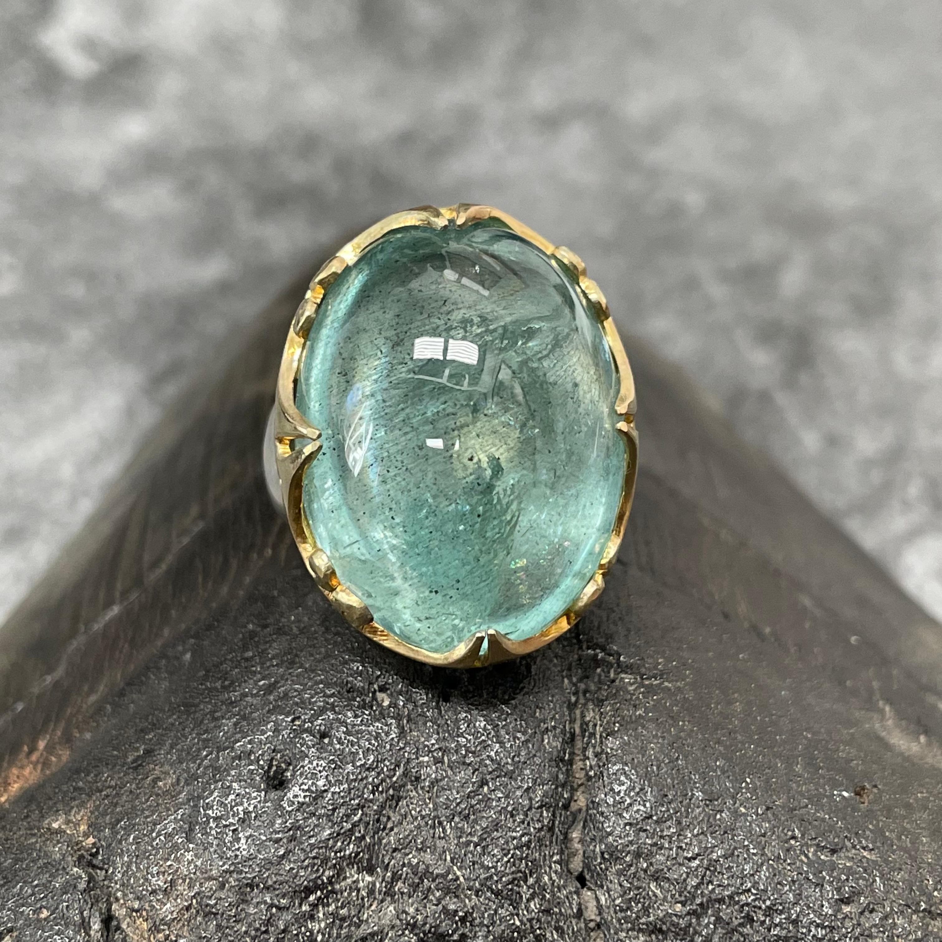 A lively green-blue large 18 x 24 mm oval cabochon aquamarine is held is a sculpted and spiraled carved 18K gold bezel atop a wide matte-finish sterling shank in this eye-catching design.  Very noticeable and unique.  Currently sized 7.  This ring
