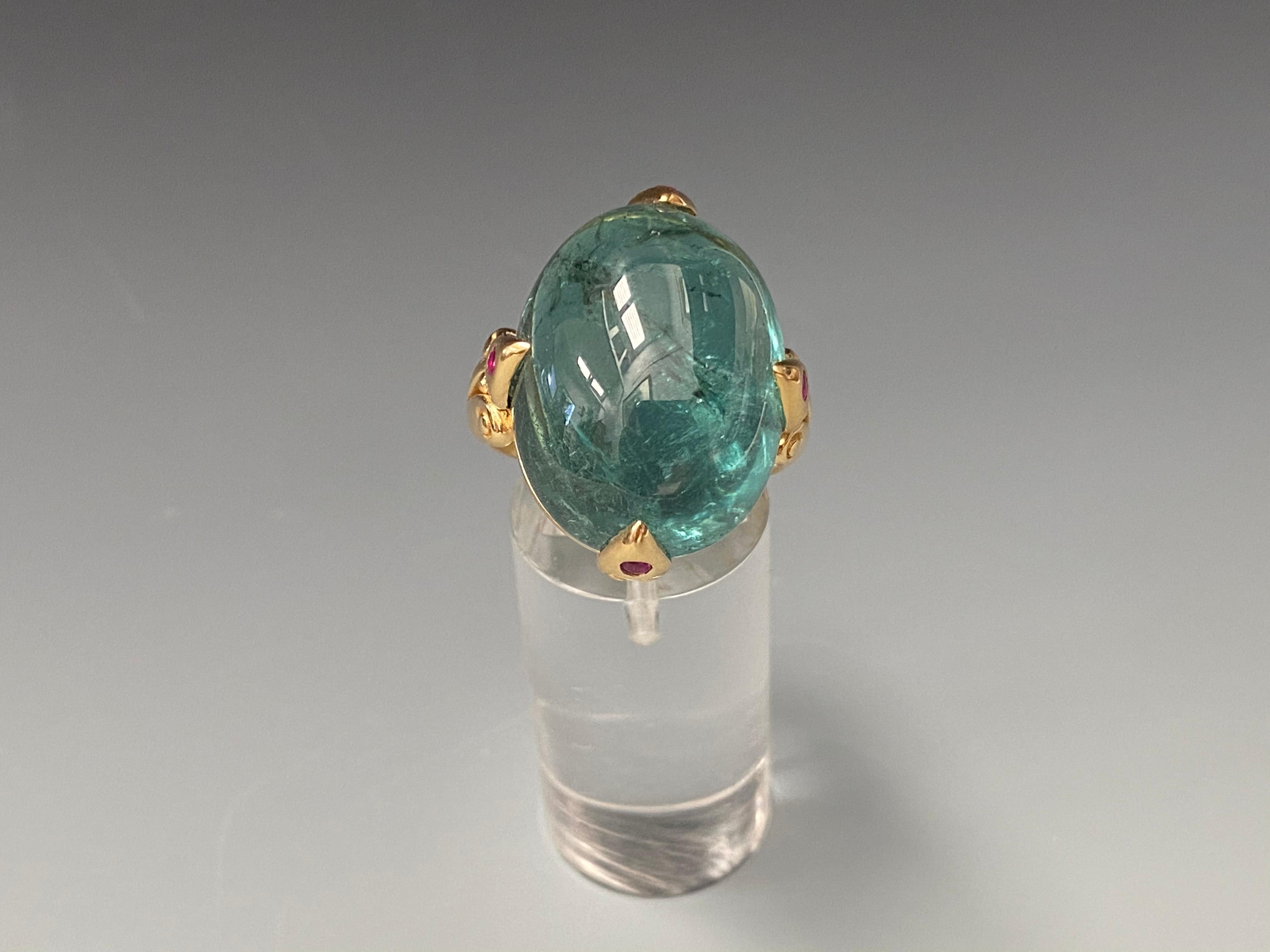 A beautiful and rare 36 carat Brazilian Indicolite Tourmaline is presented with 4 ruby accented carved prongs with a double spiral ancient inspired shank in this one of a kind Steven Battelle design. Indicolite is the indigo- or neon-blue colored