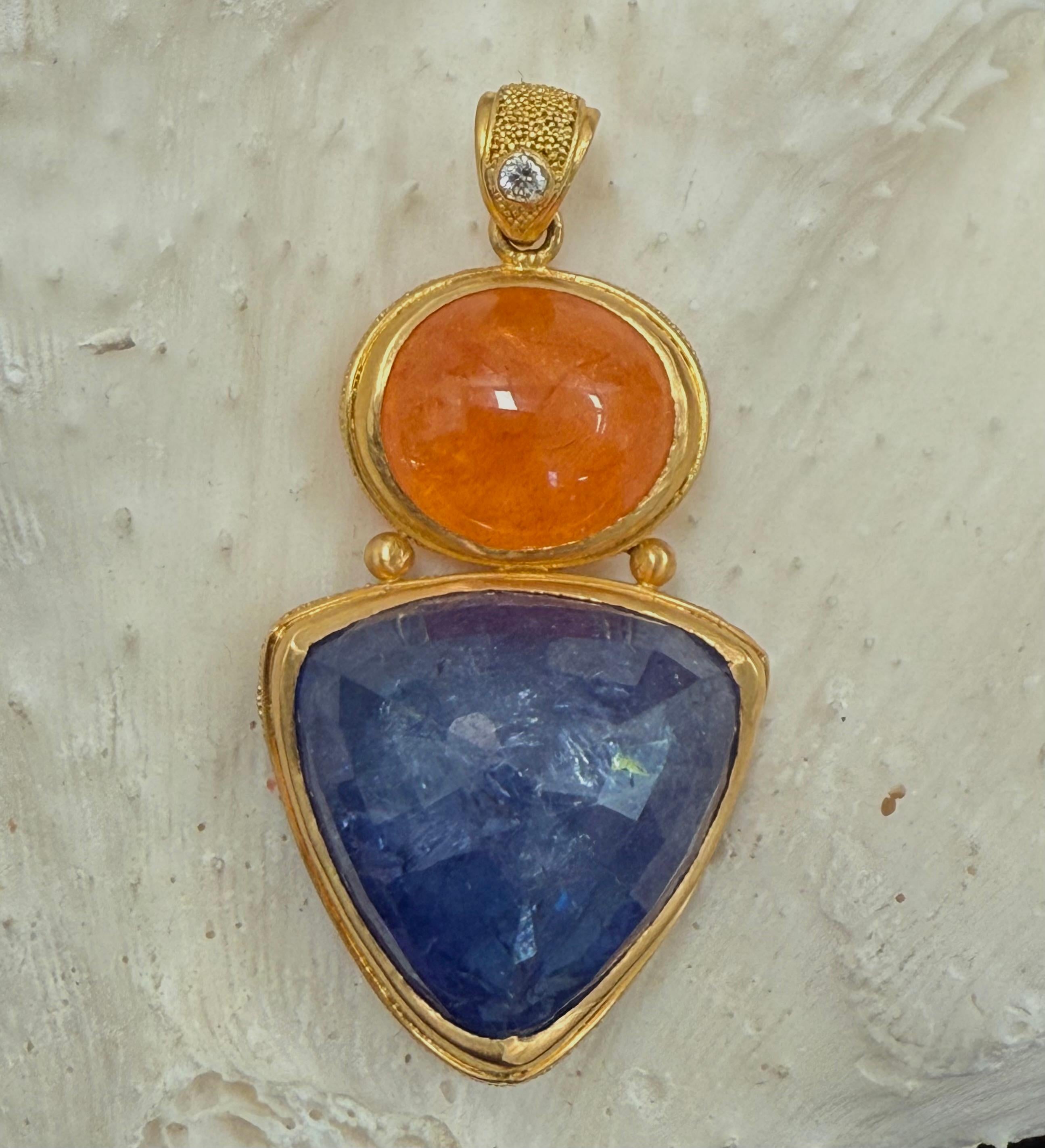 Une Tanzanite trillium de 14 mm à facettes de 25,9 carats est suspendue sous un cabochon de grenat spessartite ovale de 8x10 mm de 11 carats serti horizontalement, associé à une bague rehaussée de diamants, dans cette intéressante juxtaposition de
