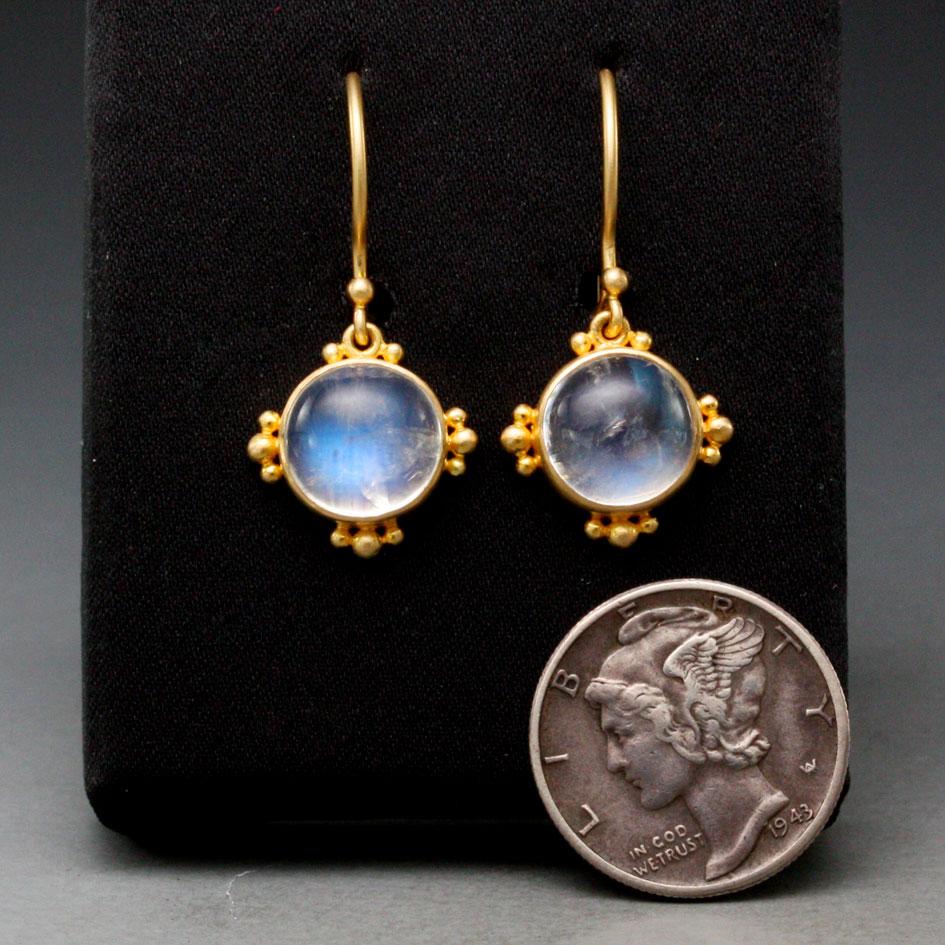 Two blue flash 9mm rainbow moonstones are set in simple matte-finish 18K gold bezels with 