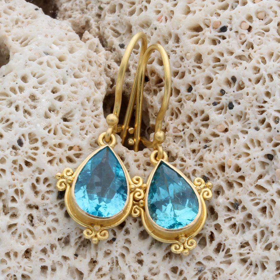 Due apatiti sfaccettate a forma di pera, luminose e brillanti, di 7 x 10 mm, sono montate in queste delicate bellezze in un'incastonatura artigianale in oro 18 carati con finitura opaca, che penzola sotto i fili per orecchie con chiusura di
