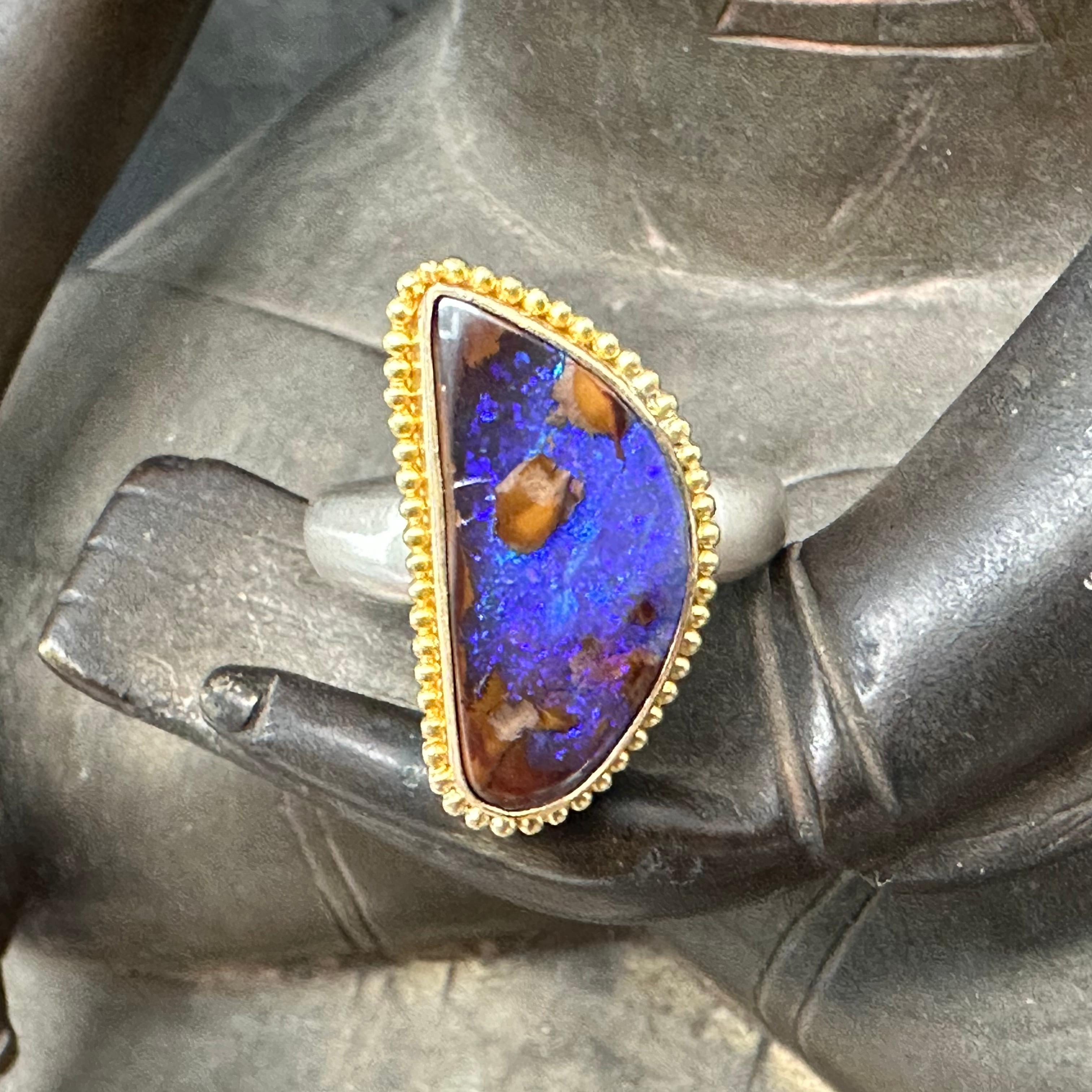 A beautiful irregular shaped 9 x 19 mm cabochon of Quipee mine Australian boulder opal displays sheens of brilliant blue again contrasting gold while set in a 