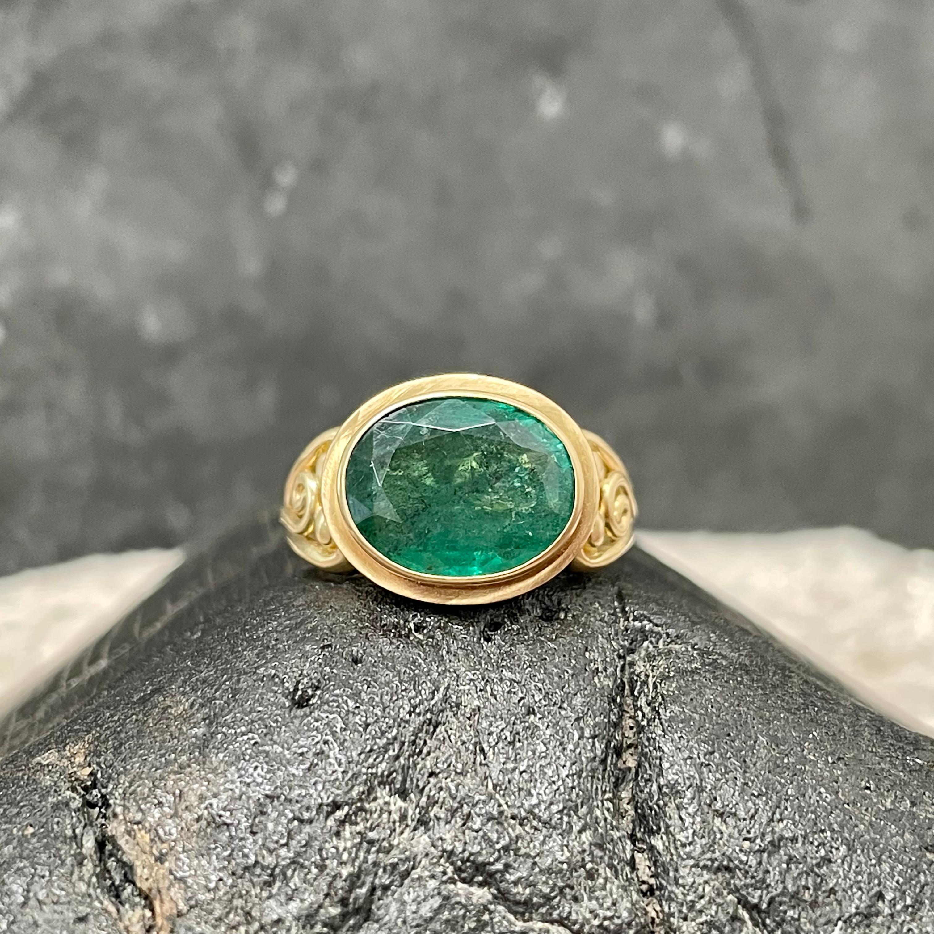 A large 10 x 12 mm oval faceted Zambian emerald rests in a 